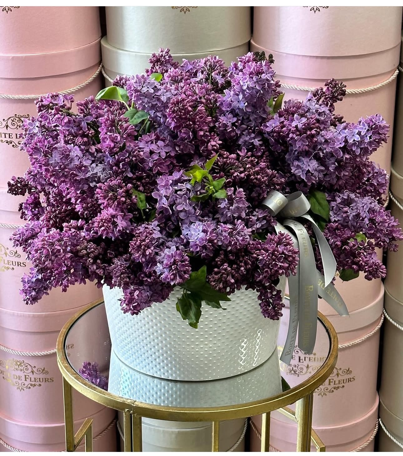 Bouquet of purple lilacs in a white hatbox with a ribbon