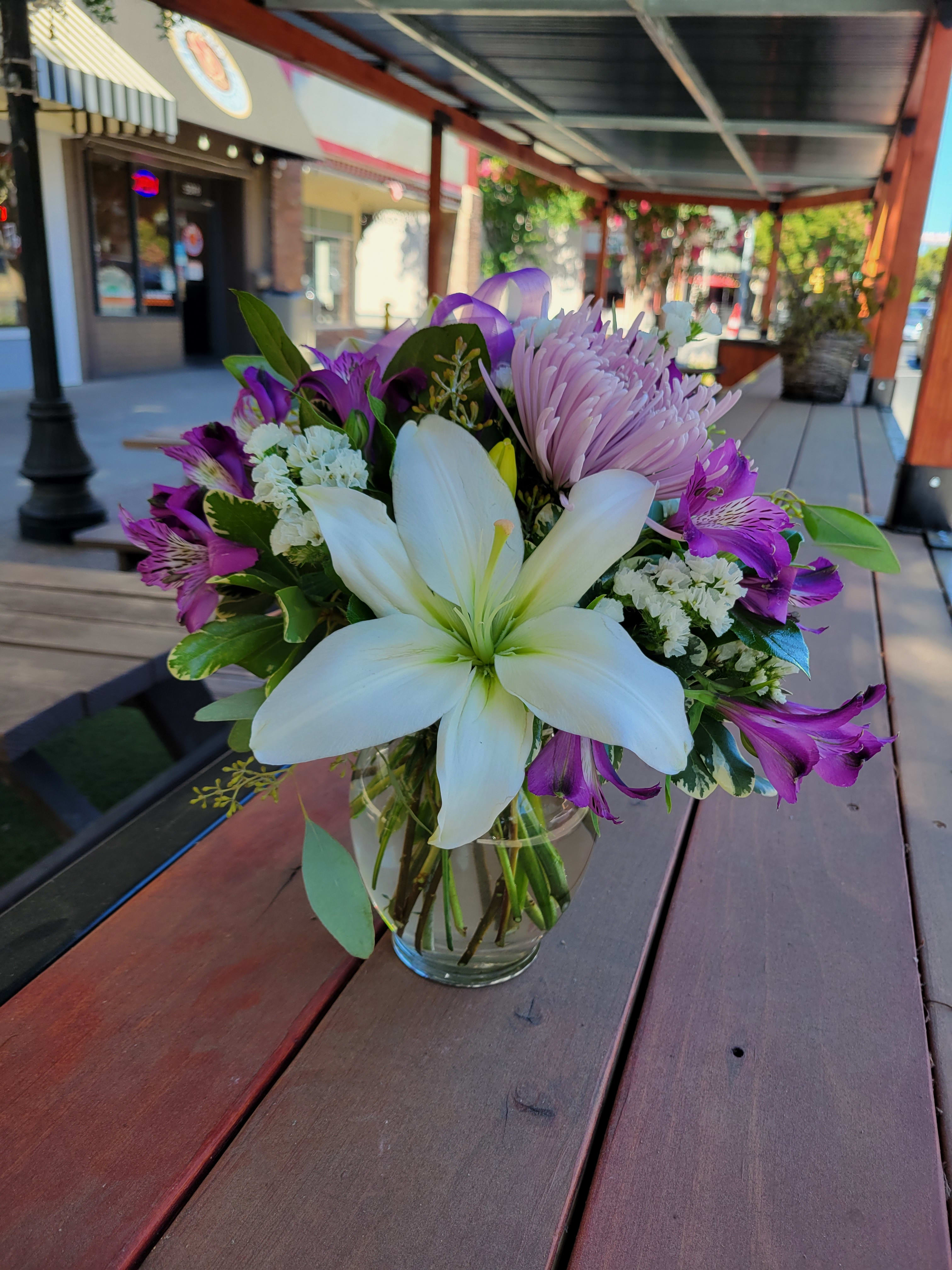 Purple Passion - This darling design is perfect for a "Just Because" or "Thinking of You" arrangement! This mix of lavender, purple, and white will bring a smile to whomever you send them to. This arrangement has white lilies, alstromeria, and chrysanthemums and statice. 