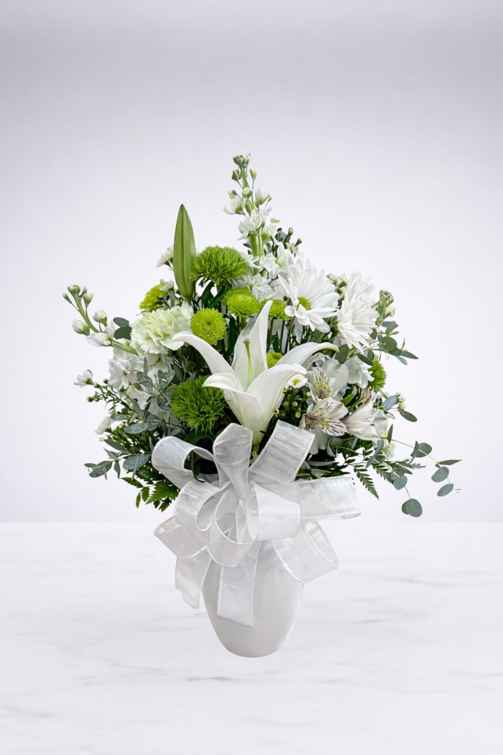 Elegant Whites  - A timeless and elegant arrangement designed in a classic white vase and finished with a soft white bow. Its clean, graceful style makes it a beautiful choice for expressing sympathy, celebrating a wedding or new marriage, honoring a loved one, or bringing a sense of peace and beauty to any space.