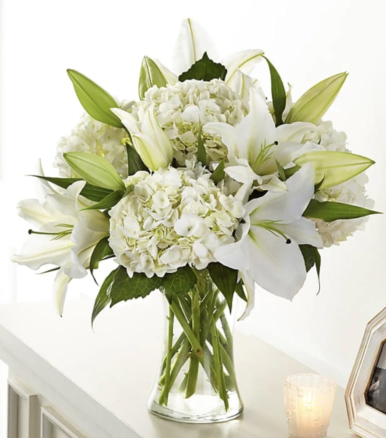 White lilies and hydrangeas arranged in a clear glass vase