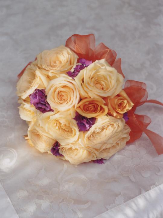 Cream rose bouquet with purple accents and orange ribbon