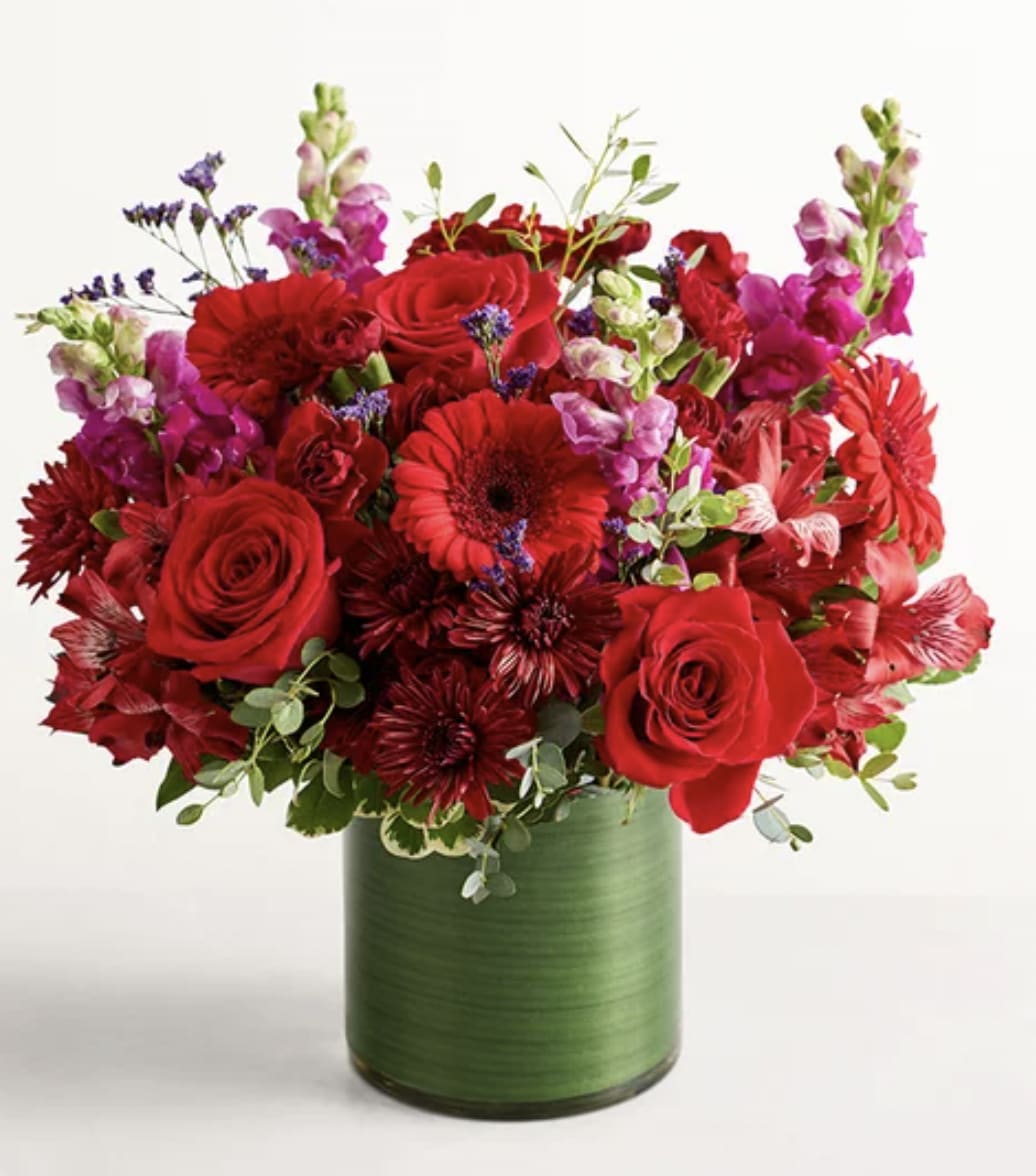 Red roses and mixed flowers in a green vase
