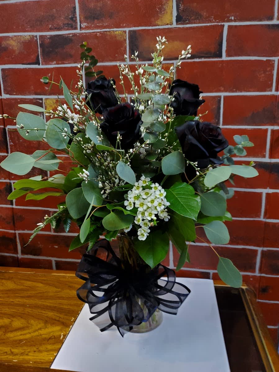 Bouquet of black roses with white filler flowers in a glass vase