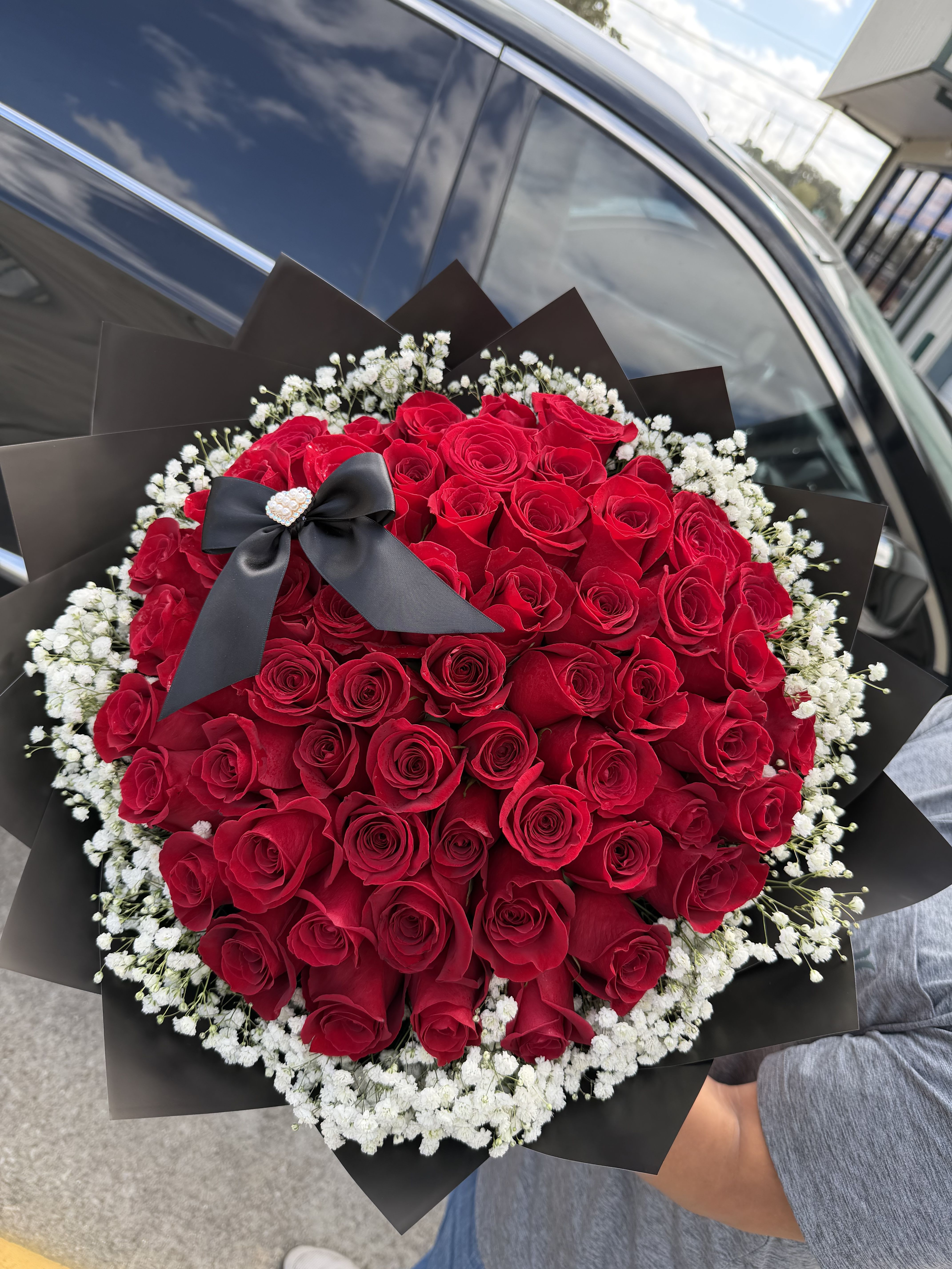 RED ALLURE  - A bouquet of 50 red roses surrounded by delicate baby’s breath, wrapped in sleek black paper. Modern romance at its finest. 