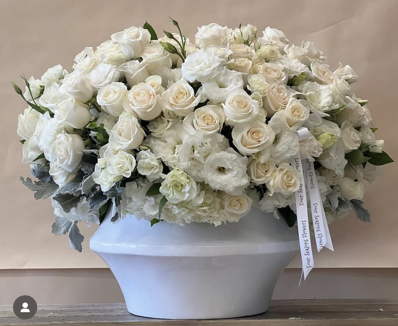Ella Luxury White &amp; Ivory Rose Floral Arrangement - Ella is a high-end, lush composition designed to make a refined statement. Featuring premium white roses, ruffled ivory spray roses, and delicate lisianthus, this elegant arrangement is layered with soft textures and subtle dimension. Accented with silvery dusty miller and styled in a chic white vase, Ella is a full, dense designer’s choice creation that brings timeless sophistication to any space.   Some florals are seasonal, if particular flower will not be available due to season, we will substitute for similar flower, composition, color pallet and value of the arrangements as closely as possible. All effort to create a floral arrangement as close to the photo shown, the actual arrangement may vary slightly in its appearance from the photo shown. If you have any questions about your order, we welcome you to call us in or email   Holiday Delivery:  Same-day delivery available. Deliveries are made throughout the day based on routing.