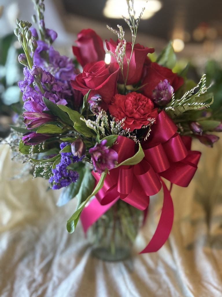 Bouquet of red roses and purple flowers with a pink ribbon