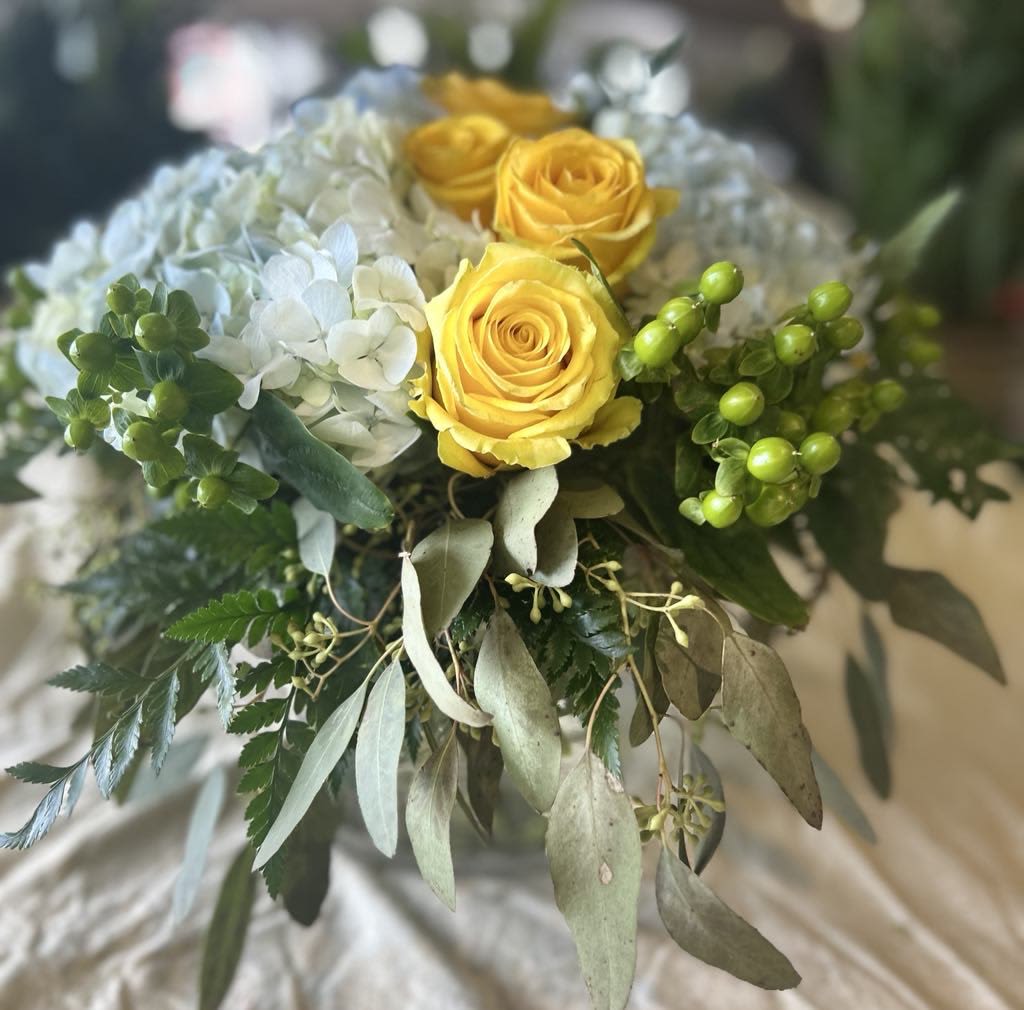 Marge - Brighten any space with our stunning floral arrangement featuring vibrant yellow roses, lush white hydrangeas, and unique green hypericum berries, all elegantly complemented by seeded eucalyptus. This exquisite combination is beautifully presented in a round clear vase, making it a perfect centerpiece for any occasion or a thoughtful gift for someone special. Elevate your decor with this fresh and lively arrangement that brings a touch of nature indoors.
