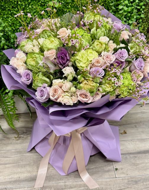 Lavender, Blush &amp; Green Rose Spring Bouquet - A stunning spring bouquet featuring fresh lavender roses, green roses, and soft blush pink roses paired with light green seasonal blooms. This fresh, garden-inspired arrangement creates a soft and elegant spring color palette. Hand-tied and beautifully wrapped in specialty paper with a coordinating ribbon, making it a perfect gift for birthdays, celebrations, or simply brightening someone’s day  Some florals are seasonal, if particular flower will not be available due to season, we will substitute for similar flower, composition, color pallet and value of the arrangements as closely as possible. All effort to create a floral arrangement as close to the photo shown, the actual arrangement may vary slightly in its appearance from the photo shown. If you have any questions about your order, we welcome you to call us or email.  