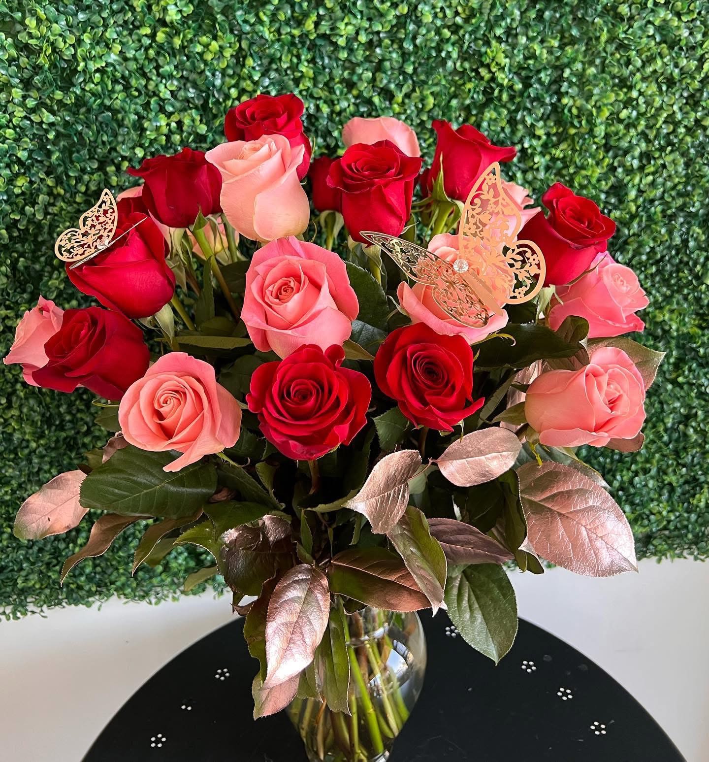 Rose Gold - Pink and red long - stem roses arranged in a vase with rose gold greenery. Standard includes 24 roses and Deluxe includes 36. 