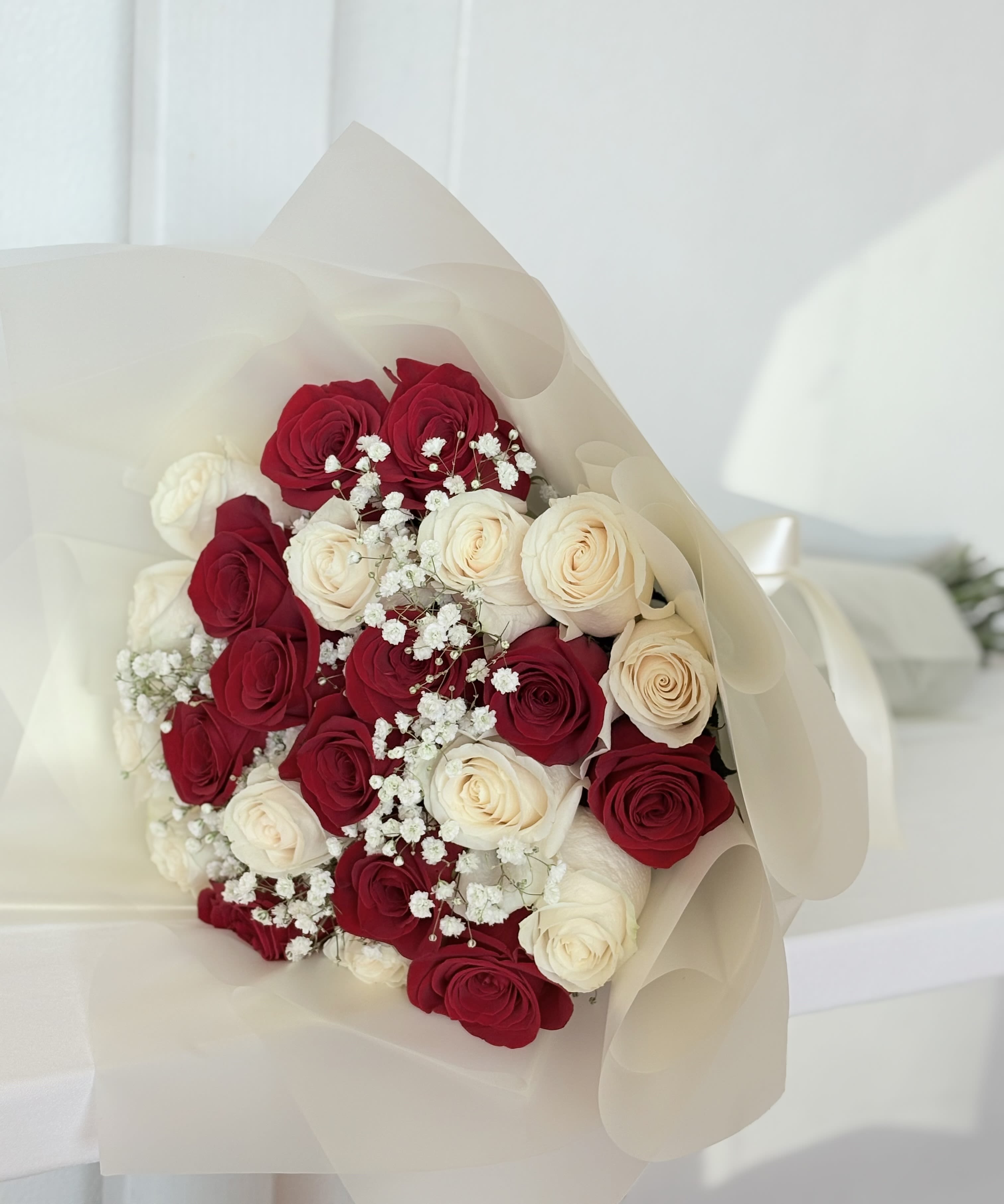 Two Dozen Red and White - 24 red and white roses with baby’s breath wrapped in waterproof wrap. Wrap color may vary due to availability. 