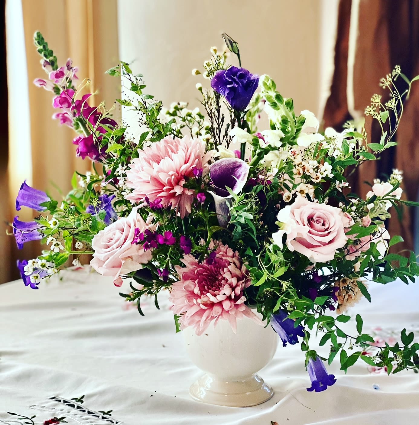 Mixed pink, purple, and white flowers arranged in a white vase