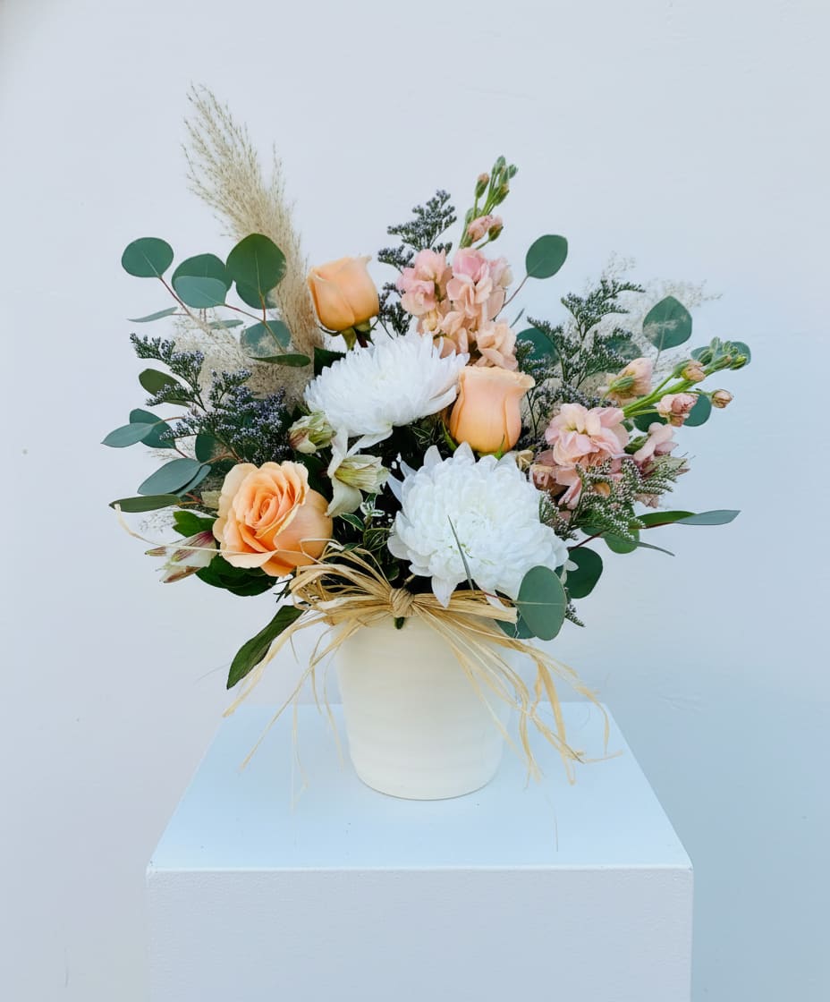 Boho Babe Arrangement - Indulge in the carefree essence of Bohemian style with the Boho Babe arrangement. Featuring Pompas plumes, dancing silver eucalyptus, and long-lasting white mums and blooms of soft peach hues, this floral masterpiece embodies a boho-chic vibe that will elevate any space with its natural beauty.
