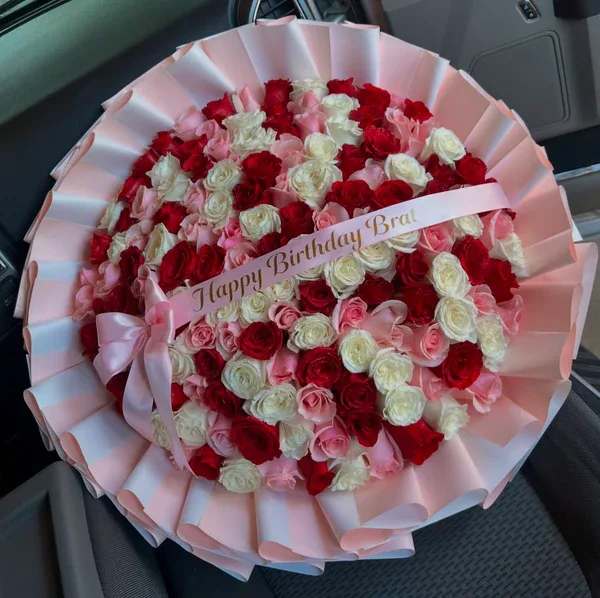 Round bouquet of red, pink, and white roses with a birthday ribbon