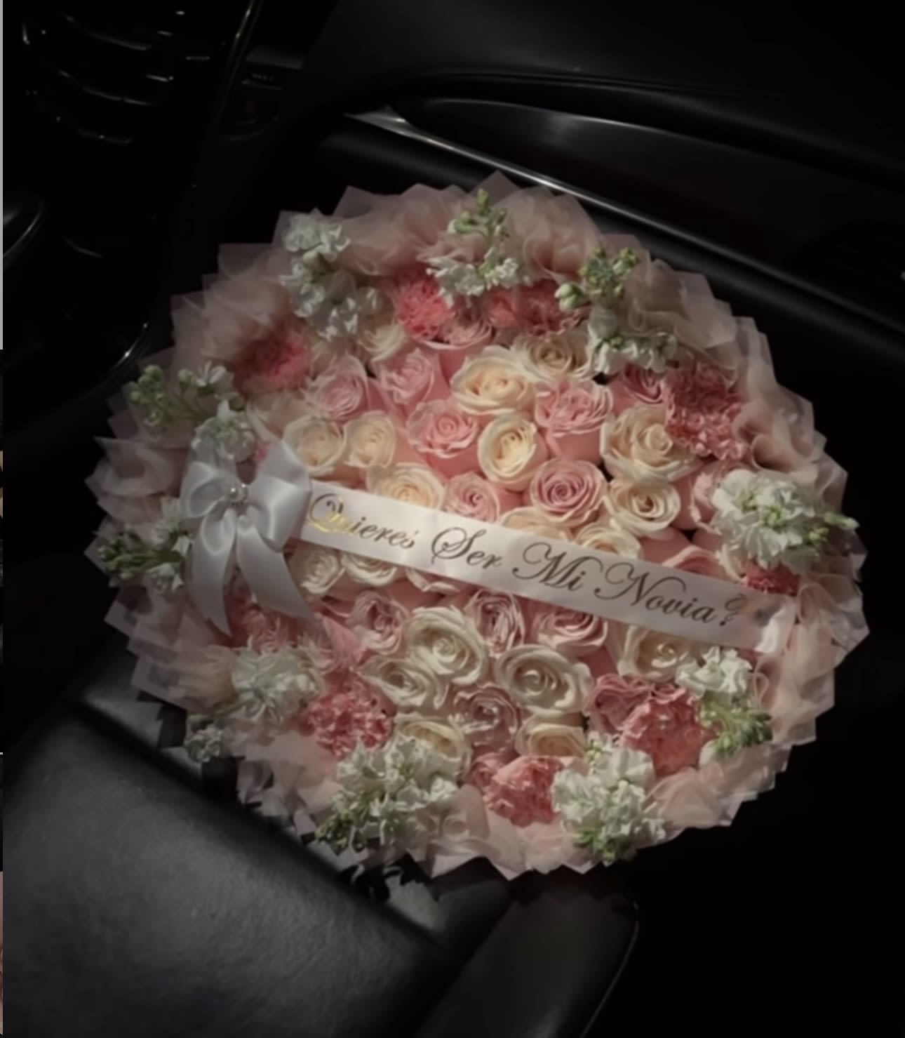 Round bouquet of pink and cream roses with a ribbon banner