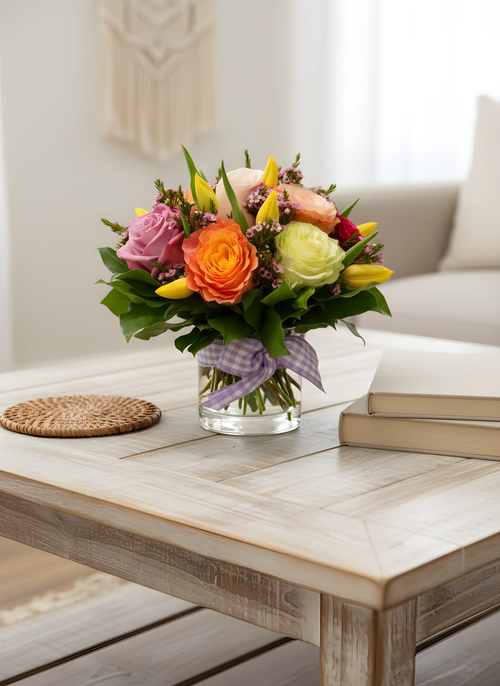 Colorful bouquet of roses and tulips in a glass vase with a purple ribbon