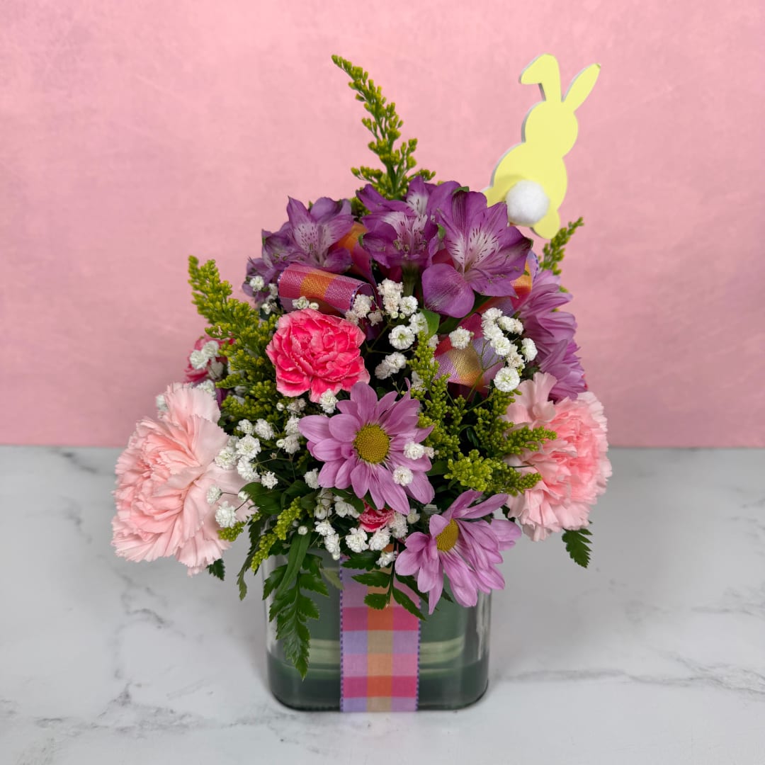 Plaid Perfection Cube - Get ready for spring with the Plaid Perfection Cube by Savilles Florist! This delightful arrangement features a variety of pink and purple blooms like daisies, carnations, and alstroemeria, perfectly nestled in a glass cube, adorned with both a colorful plaid ribbon and a matching bow, along with a cute little bunny inspired pick! This arrangement would make the perfect gift for lots of different occasions, and is a great way to bring some springtime joy into a home or business.