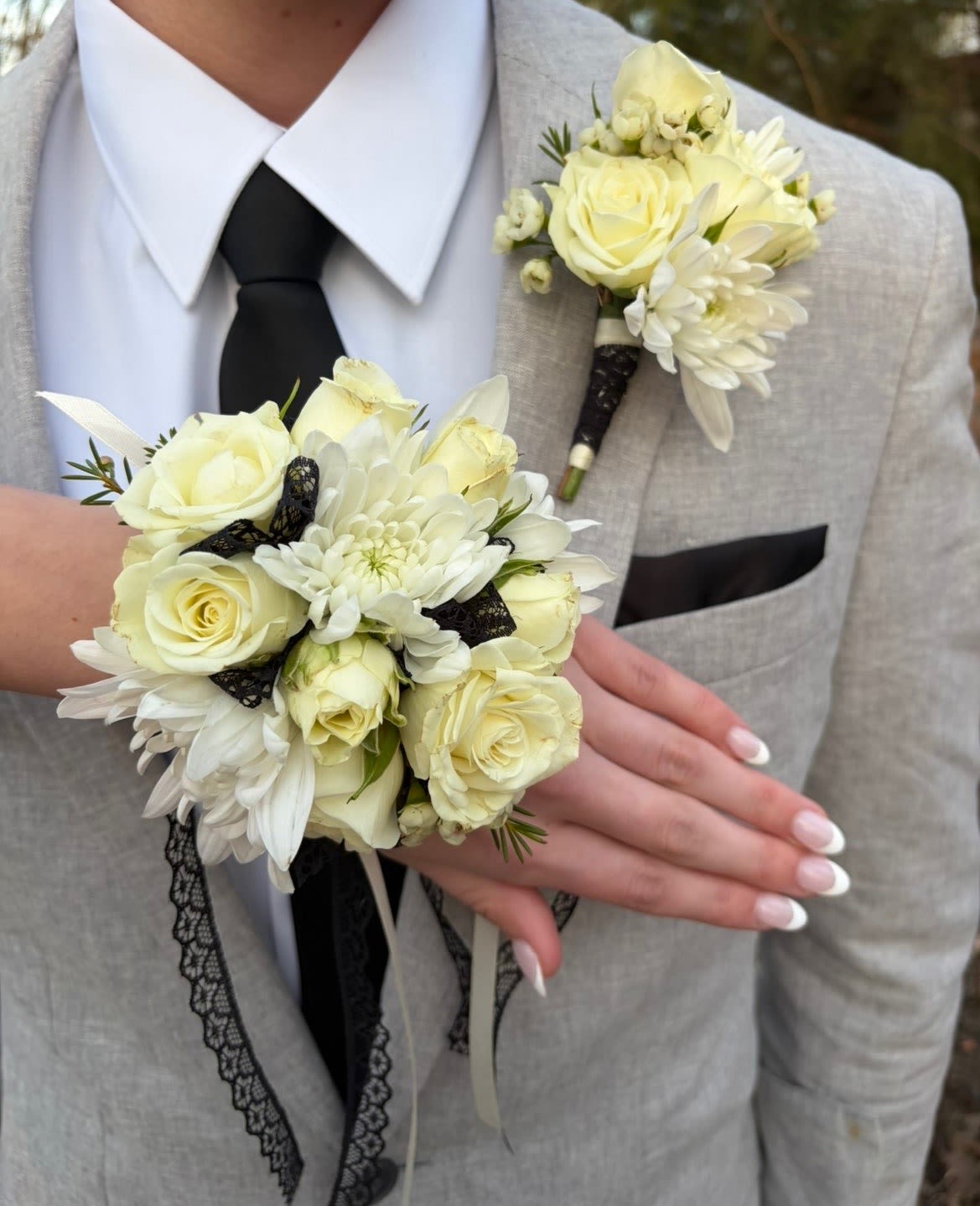 White rose boutonniere and matching wrist corsage on a light suit