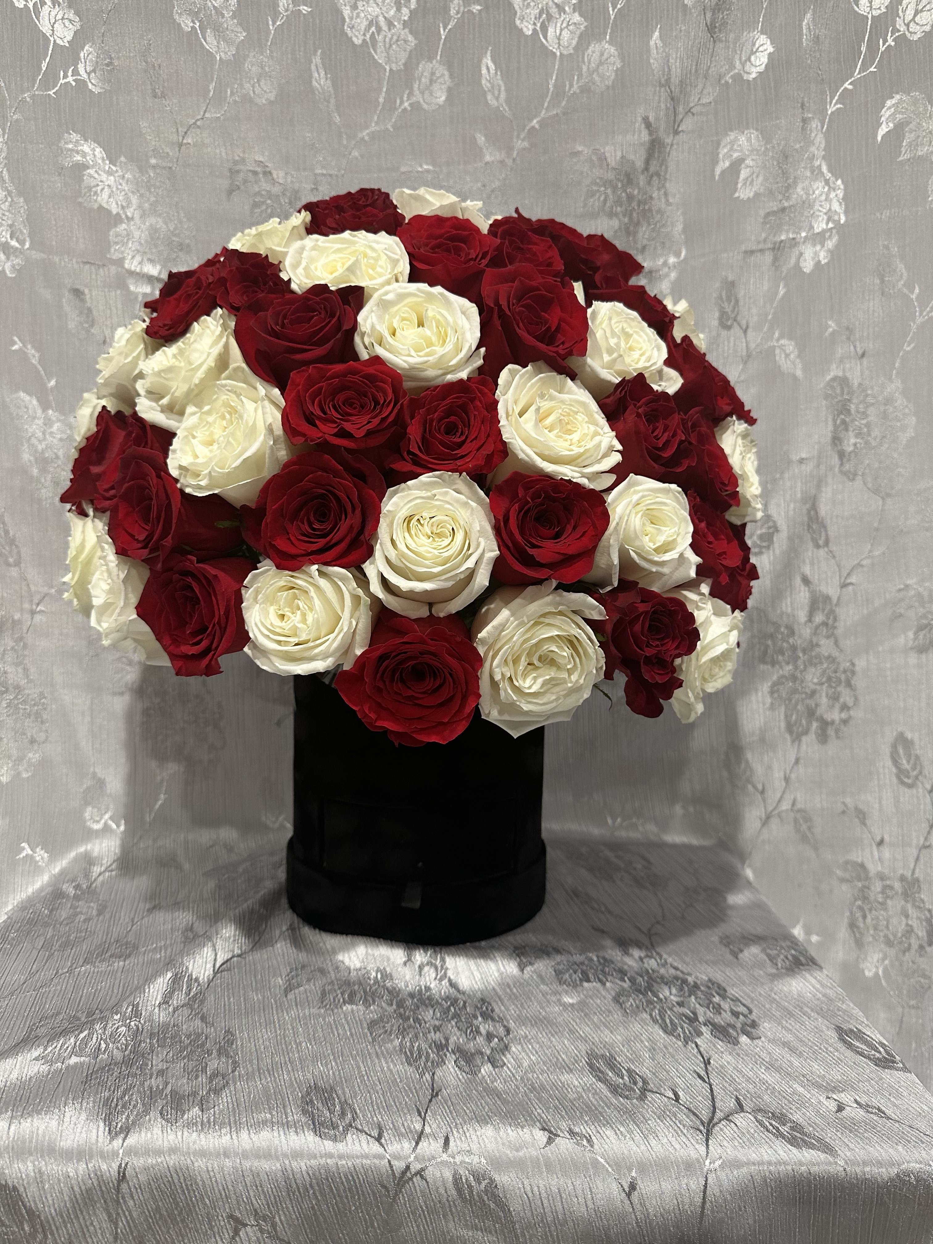 Red and white rose arrangement in a black box