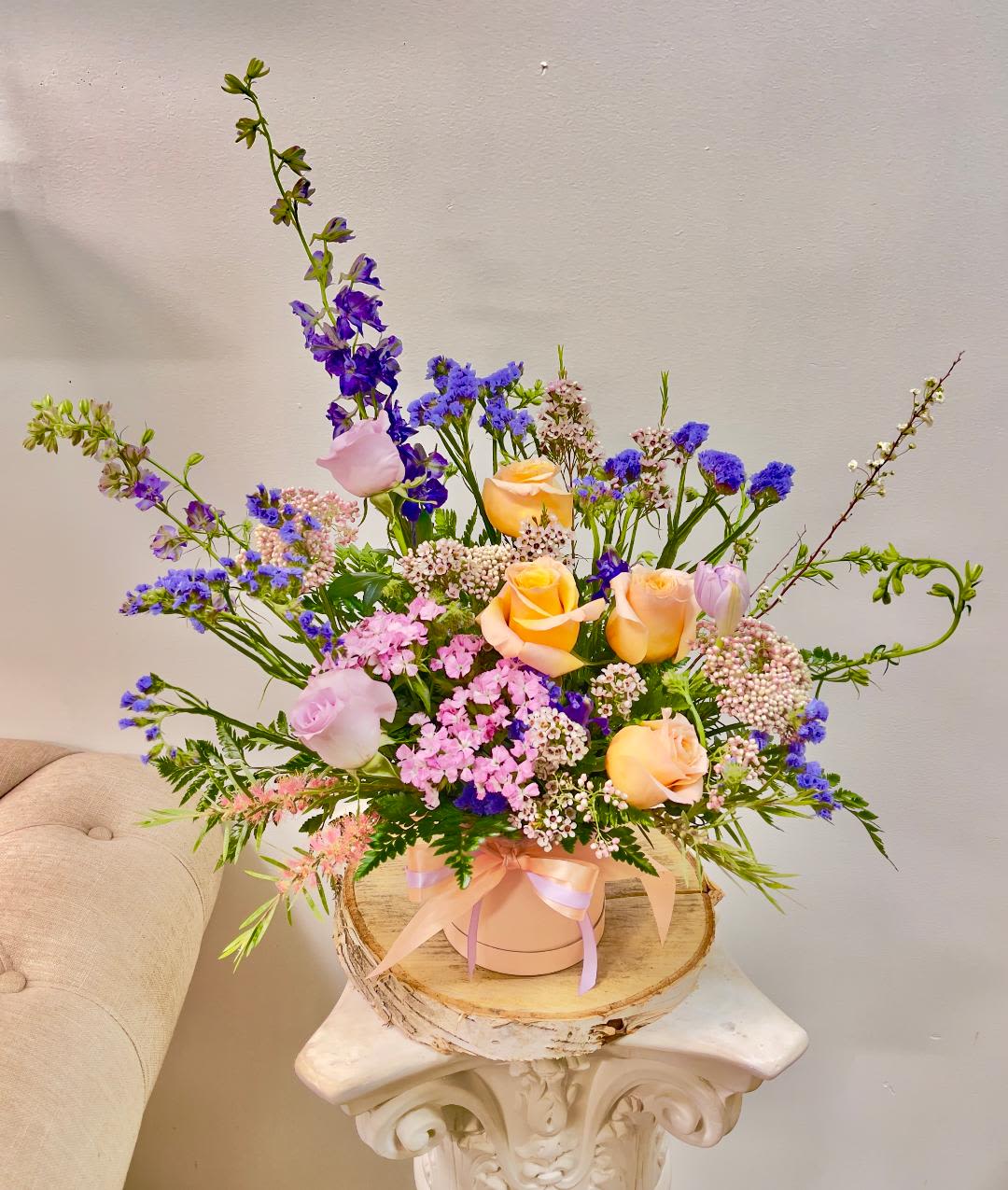 Rosalinda -  Product Information Theme Colors: Pastel peach lavender  Featured Blooms: Roses, Delphinium, Daisy, bloom ,Tulips, and greeneries in Light pink box.  HK Flowers have a uniqueness of florals and seasonal blooms, certain flowers or colors may not be available as each season affects the availability, color, size, and shape of each floral bloom. Some flowers may be substituted accordingly.  Photos are used as a reference for the color palette and is NOT indicated of the final product. We ask for your trust in us that we will pick out the best seasonal available blooms, while still capturing the arrangements' theme and colors mentioned above