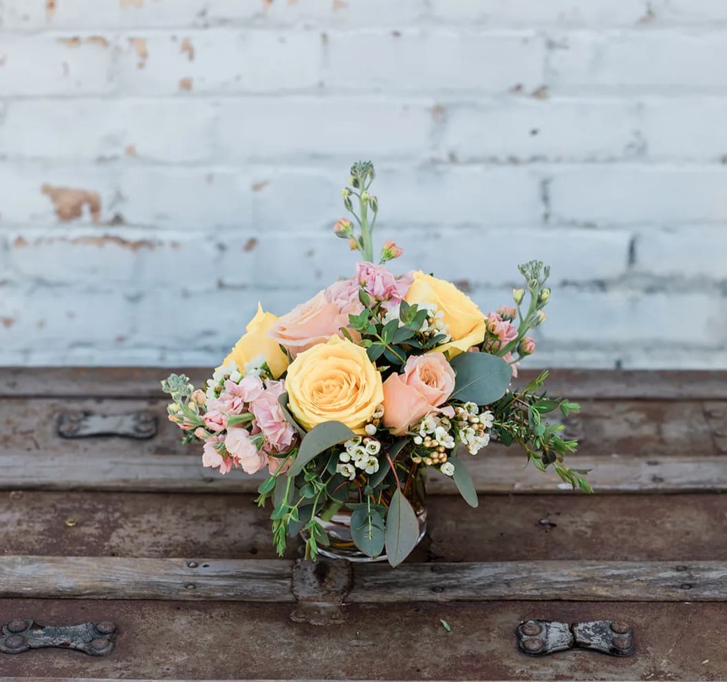 Bouquet of yellow and peach roses with pink flowers in a glass vase