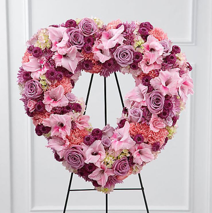 Open Heart - Easel - The Eternal Rest™ Standing Heart bursts with love and sweet comfort to honor the deceased at their final farewell service. Lavender roses, pink carnations, purple button poms, lavender chrysanthemums, pink gladiolus and pink hydrangea are beautifully arranged in the shape of a heart and displayed on a wire easel to create a stunning display of warm affection that will last in the hearts of friends and family for years to come.