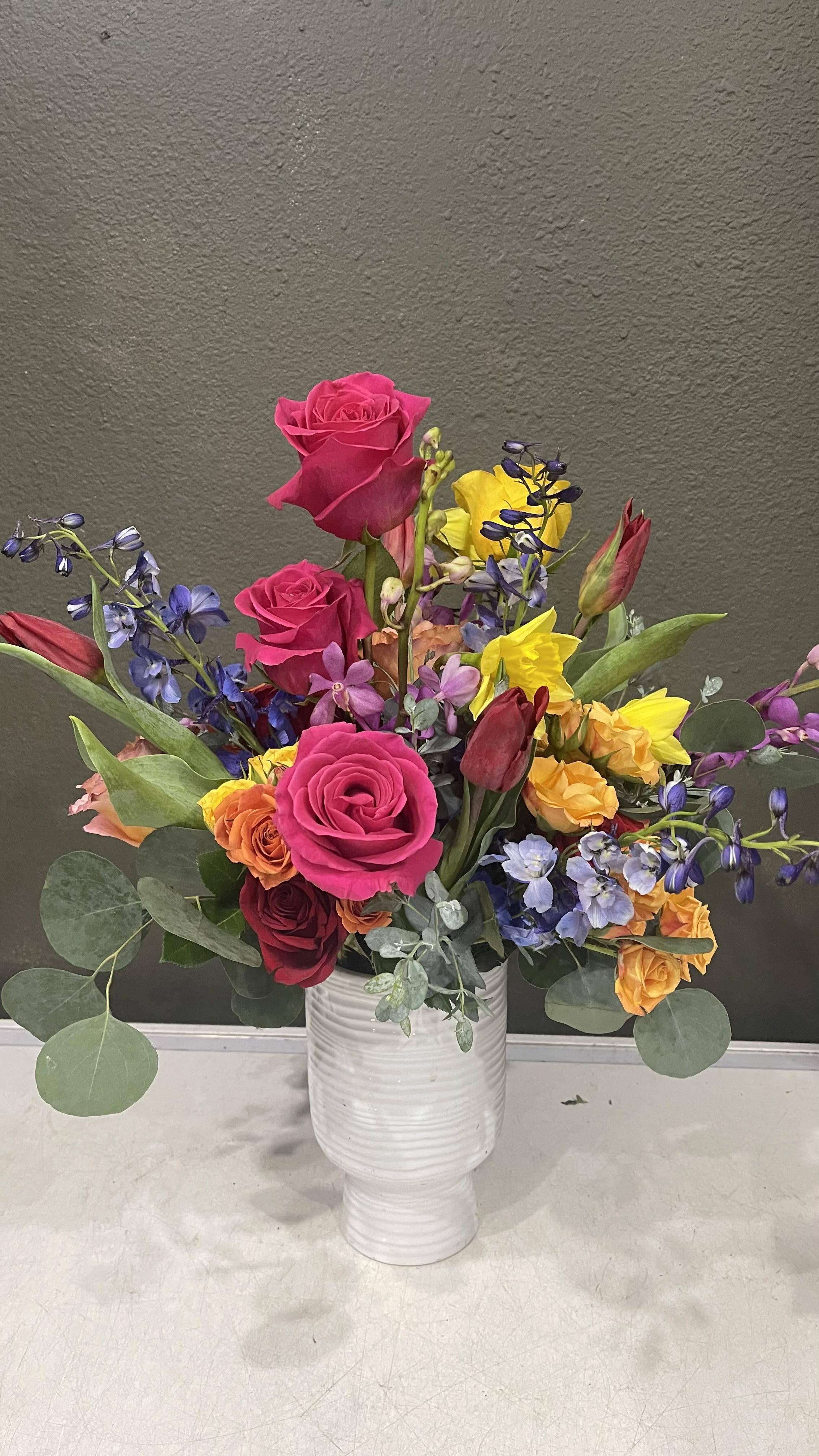 Seville - Fun and feminine, this arrangement is sure to bring excitement to any recipient. Created in a quality textured ceramic vase and made up of colorful roses, anemones, snapdragons, a colorful decorative palm, and sweet fragrant hyacinths (when in season).  Perfect flowers for birthdays, "get well soon," new baby, congratulations, romantic gestures, and "Thank you." Also a beautiful wedding palette.  Available for delivery in Seattle, Bellevue, Shoreline, and surrounding areas. Available for delivery in all neighborhoods in Seattle including Magnolia, Ballard, Fremont, Downtown, Queen Anne, Crown Hill, U District, West Seattle, International District, Capitol Hill, Pioneer Square, Beacon Hill, Columbia City, Georgetown, etc. 