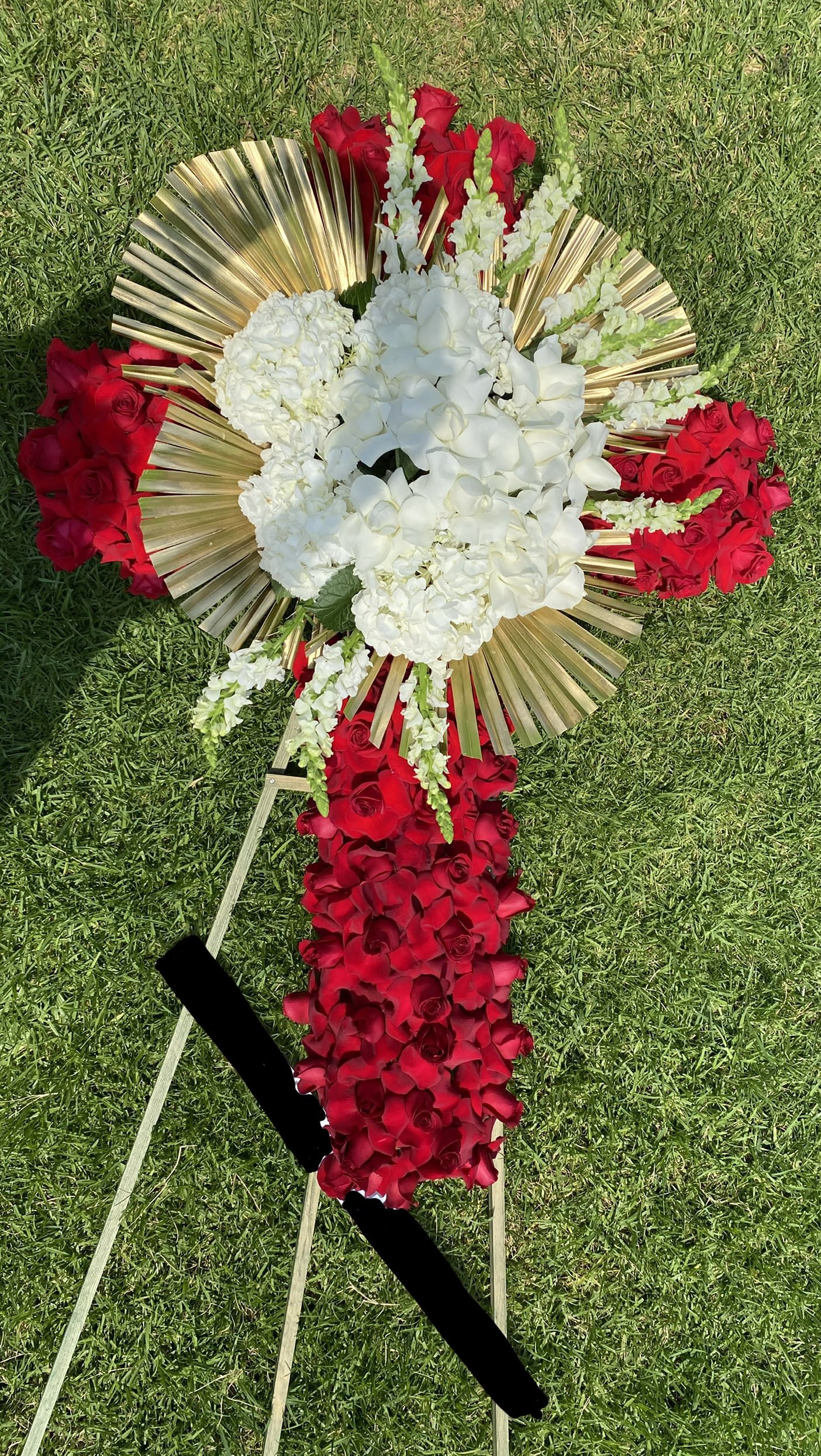 Forever Cross - A Red and white tribute, this cross funeral spray is pure and tranquil. Featuring a variety of white flowers, Red Flowers, and white orchids, this elegant easel compliments the beauty of life.