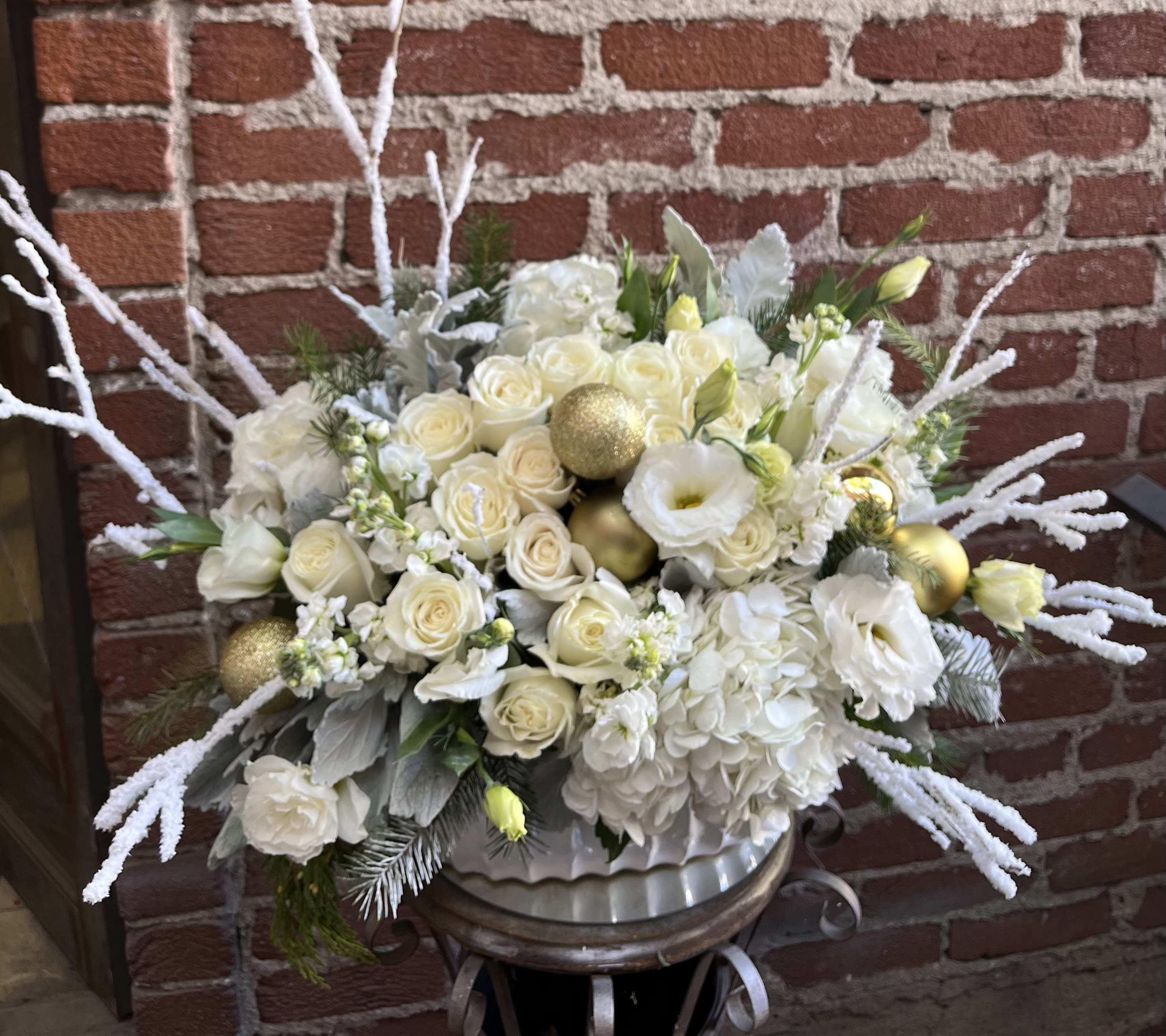 Noel - Buzzy Bee Flowers - Introducing "Noel Elegance" Christmas Flower Arrangement – a harmonious blend of nature's finest blooms, meticulously curated to bring the spirit of the season into your home. Crafted with precision and love, Noel Elegance is not just a floral arrangement; it's a festive symphony of colors and fragrances that will enchant your holiday celebrations.  Key Features:  Timeless Elegance: Noel Elegance features a sophisticated combination of winter blooms, including pristine white lilies, velvety red roses, and delicate touches of evergreen foliage. The arrangement exudes a timeless charm, making it a perfect centerpiece for your Christmas festivities.