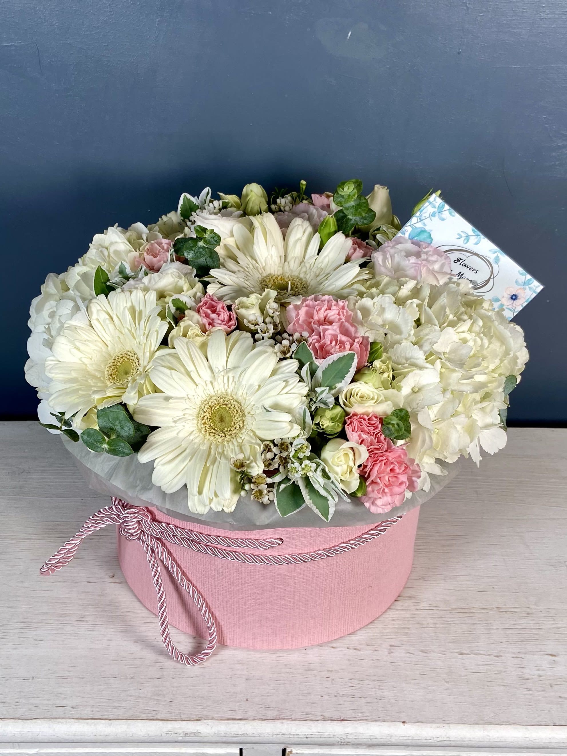 Gerberas -S - The "Gerberas -S" arrangement is a stunning arrangement in the box that features a delightful mix of white hydrangeas, vibrant gerbera daisies, soft pink carnations, and lush greenery, all beautifully complemented by delicate spray roses.  STANDARD size is shown in the picture.