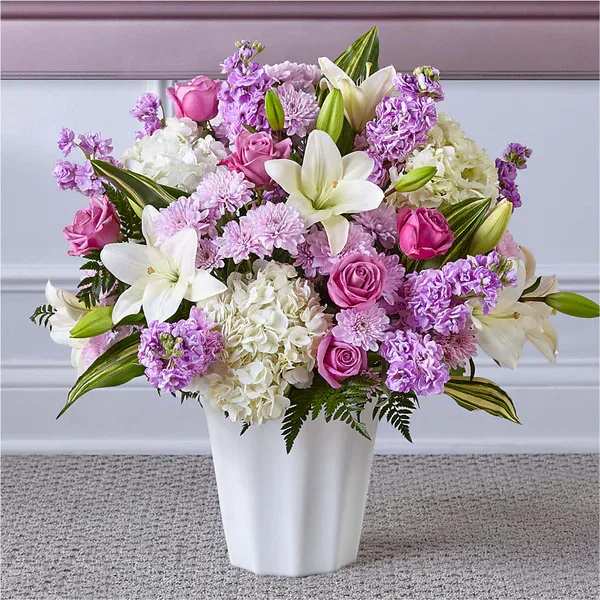 Lavender and white bouquet with lilies, roses, hydrangeas and mums in a white vase