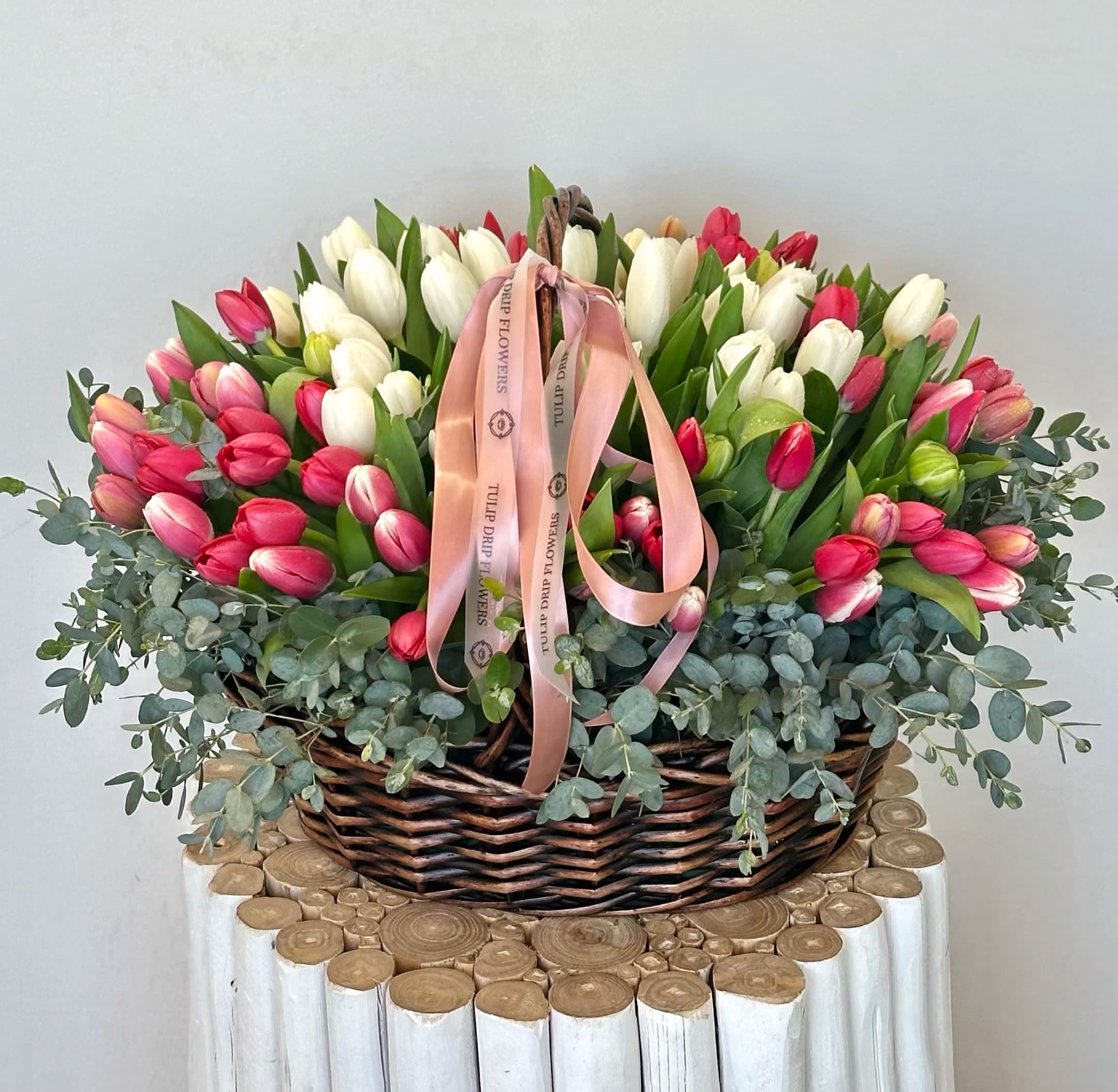 Spring Tulip Garden Basket - Bring the charm of spring into any space with our Spring Tulip Garden Basket. Bursting with fresh red, white, and pink tulips, this lush arrangement is artistically styled with eucalyptus in a handwoven basket. Perfect for birthdays, thank you gifts, or simply brightening someone’s day. Same-day tulip delivery available. 