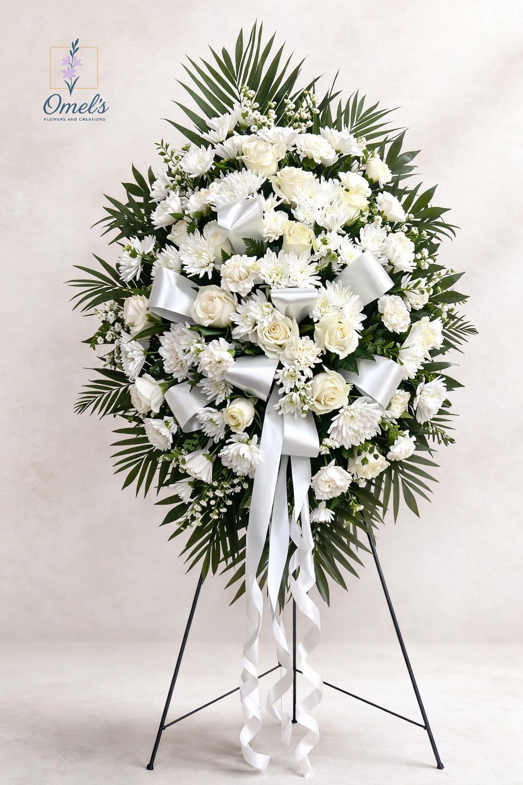 Pure Grace Standing Spray - The Pure Grace Standing Spray is a timeless and elegant tribute designed to honor a life with dignity and peace. This classic standing arrangement features pristine white roses, white chrysanthemums, and delicate accent blooms, beautifully arranged among lush palm fronds and fresh greenery.  Finished with a flowing white satin ribbon, this design symbolizes purity, remembrance, and eternal love. Its traditional teardrop shape creates a graceful presentation, making it a meaningful choice for funeral services, memorial gatherings, or celebration of life ceremonies.  Handcrafted with care and compassion, this arrangement offers comfort and beauty during a heartfelt farewell.