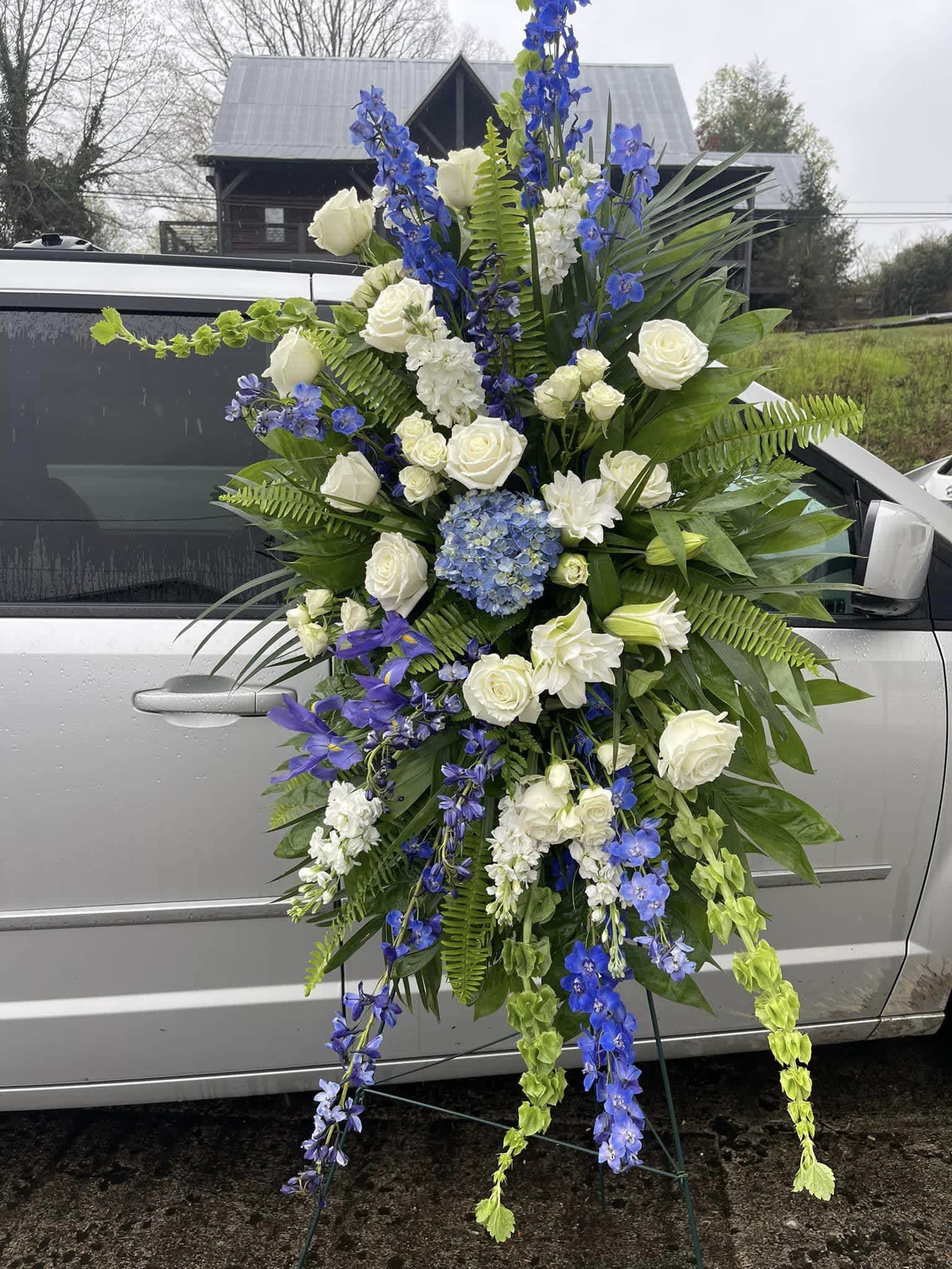 large sympathy spray white and blue - tall standing spray with white roses, bells of Ireland, iris, blue delphinium, blue hydrangea other flowers