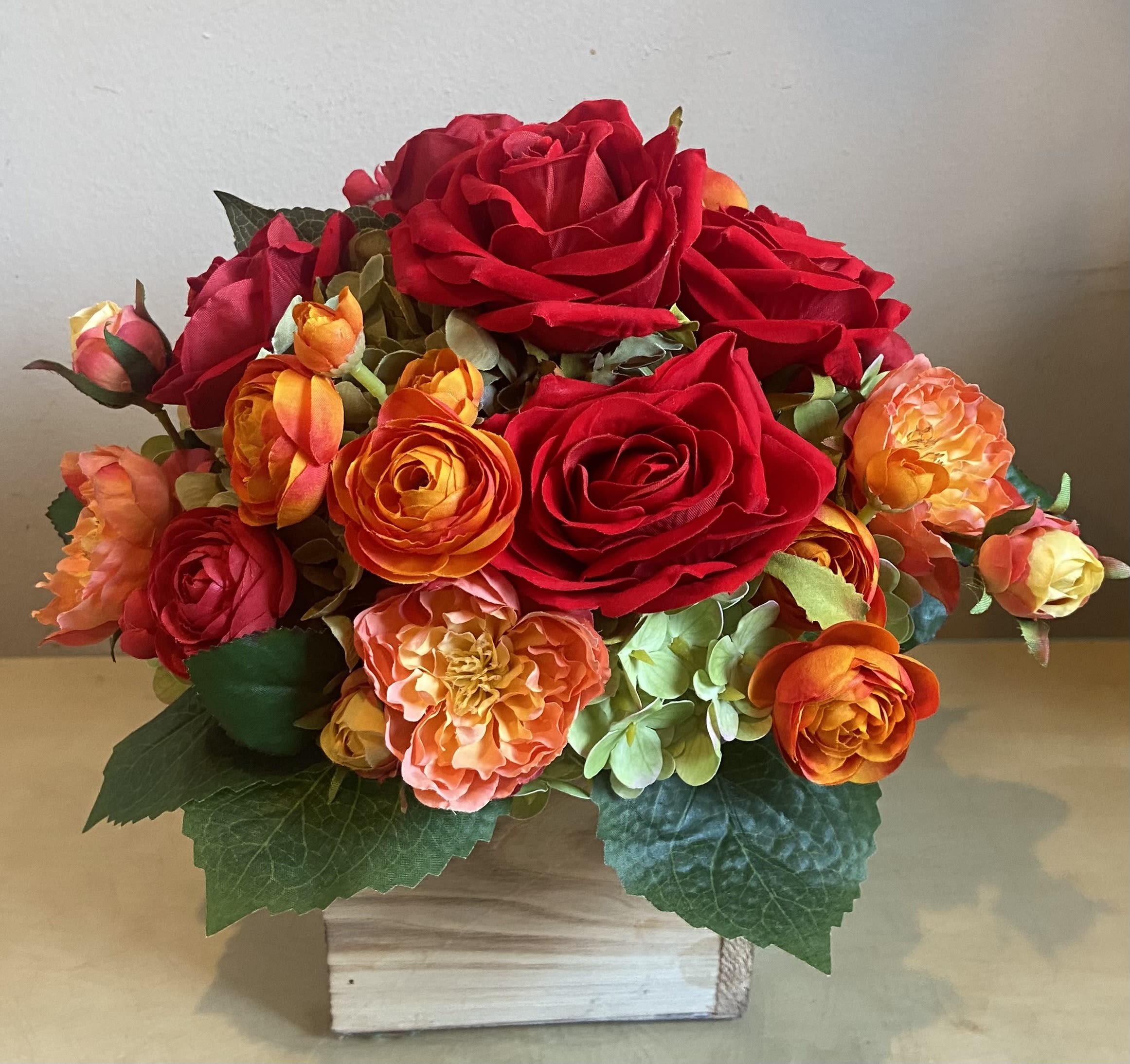 Radiant - Silk Floral Design - Stunning Silk arrangement of radiant reds and vibrant orange roses &amp; ranunculus in a bed of green hydrangea designed in a rustic wood container.