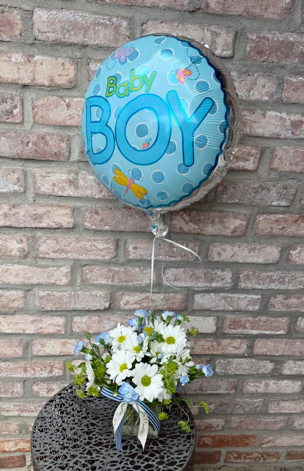 Baby Boy Bundle - Celebrate the life of a new baby boy with our darling bundle options! Arrangement is designed in a rectangular glass vase. Filled with sweet daisies and blue pixies. Deluxe and Premium include yellow spray roses added. Every option comes with a baby boy balloon, style may vary. See photos and descriptions for upgraded options. 