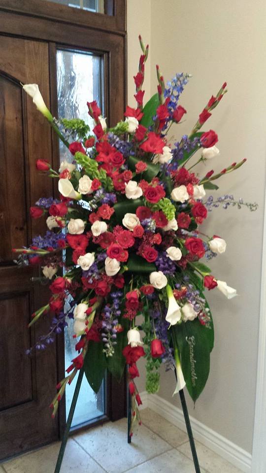 Eternal Valor Easel Spray by Simply Flowers - A stunning tribute for a Patriot and friend. This gorgeous design is full of fresh Roses, Calla lilies, Delphinium, Gerbera Daisies and more. Giving honor to the deceased. 