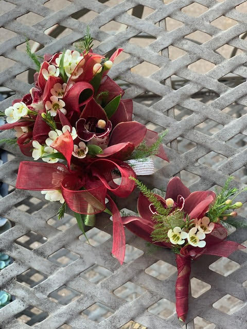Cymbidium orchids corsage and boutonniere set - Cymbidium orchids corsage and boutonniere (examples for customers) We pre-order over Florals with our growers two weeks in advance prior to a school dance. Select your color of ribbon of your choice. Corsage- $38.00 Boutonniere- $21.00 -Any add-ons such as delphinium, rhinestone, double ribbon or magnetic boutonnieres are subject to an addition fee
