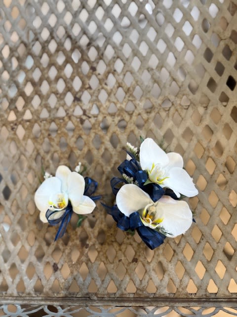 Phalaenopsis orchids Corsage and Boutonniere  - White  orchids Corsage and Boutonniere (examples for customers) We pre-order over Florals with our growers two weeks in advance prior to a school dance. Select your color of ribbon of your choice. Corsage- $45.00 Boutonniere- $23.00 -Any add-ons such as delphinium, rhinestone, double ribbon or magnetic boutonnieres are subject to an addition fee