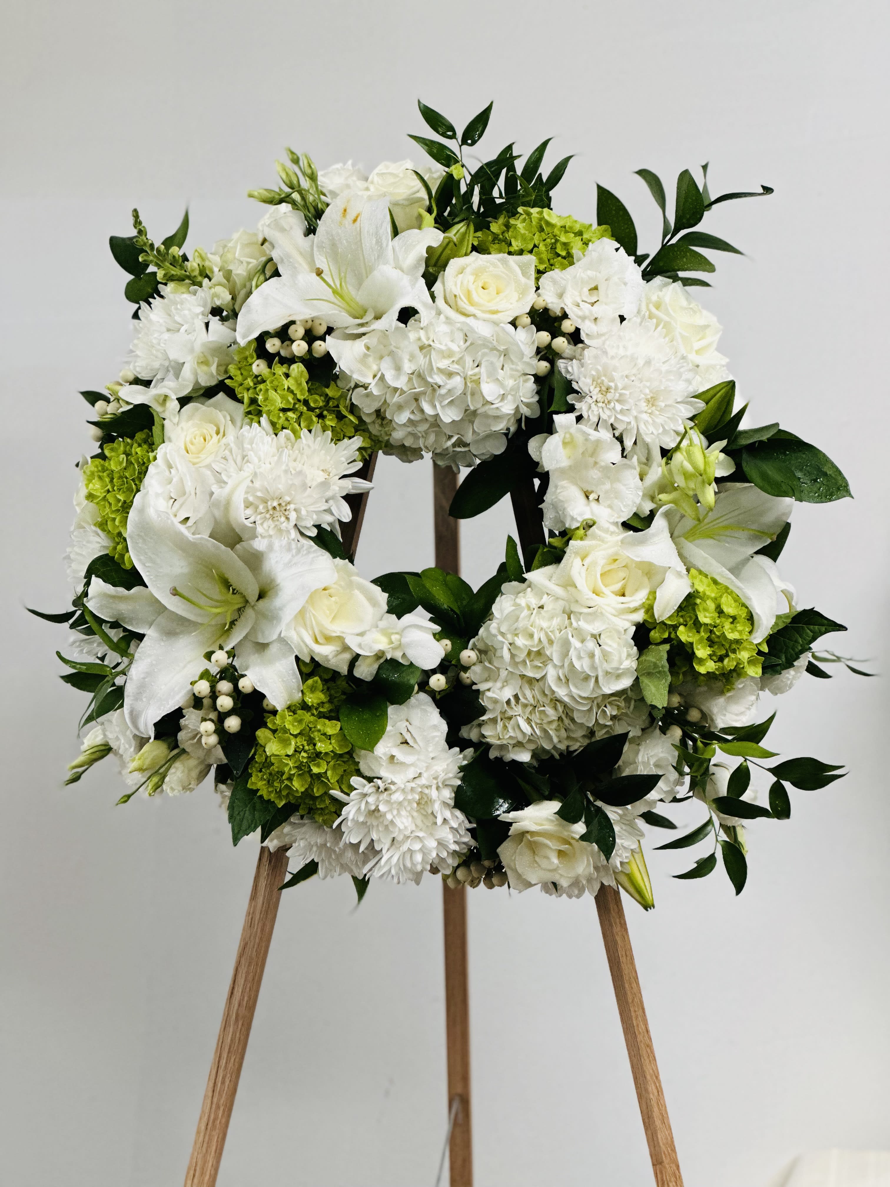 Green and White Wreath - White blossoms, lush greens create a classic wreath to convey your sympathy for loved ones. Picture Shown is Premium.