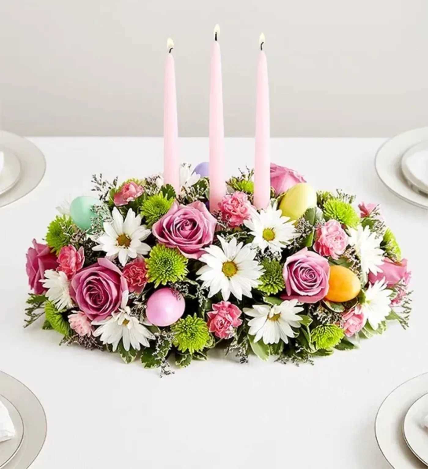 Easter Centerpiece  - Easter celebrations call for beautiful flowers. Our classic centerpiece is filled with pastel blooms and accented by colorful plastic Easter eggs for a playful touch. Elegant taper candles finish off this charming arrangement, which is sure to be the bright spot of the holiday table.