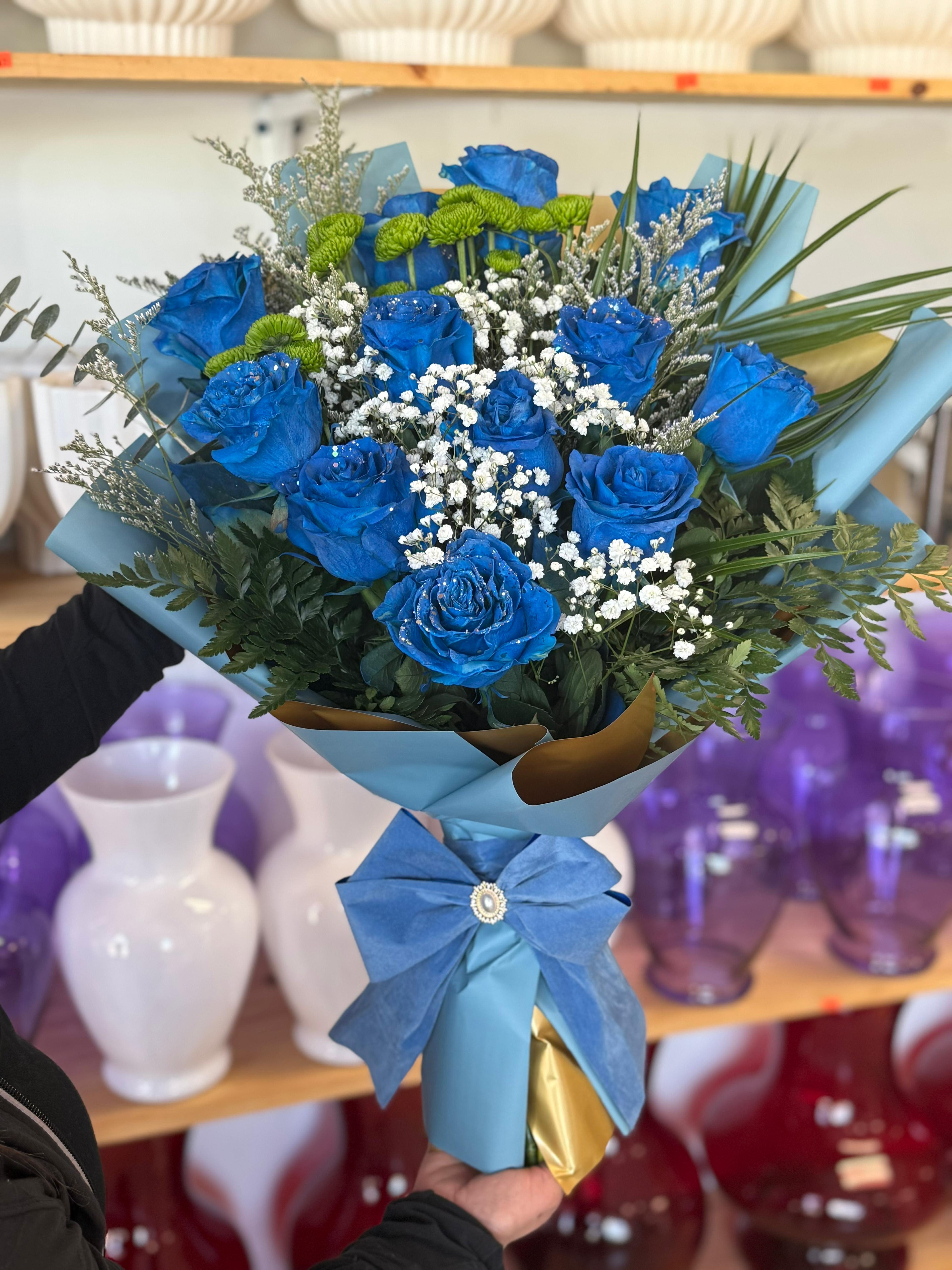 Blue roses with white baby's breath in a wrapped bouquet