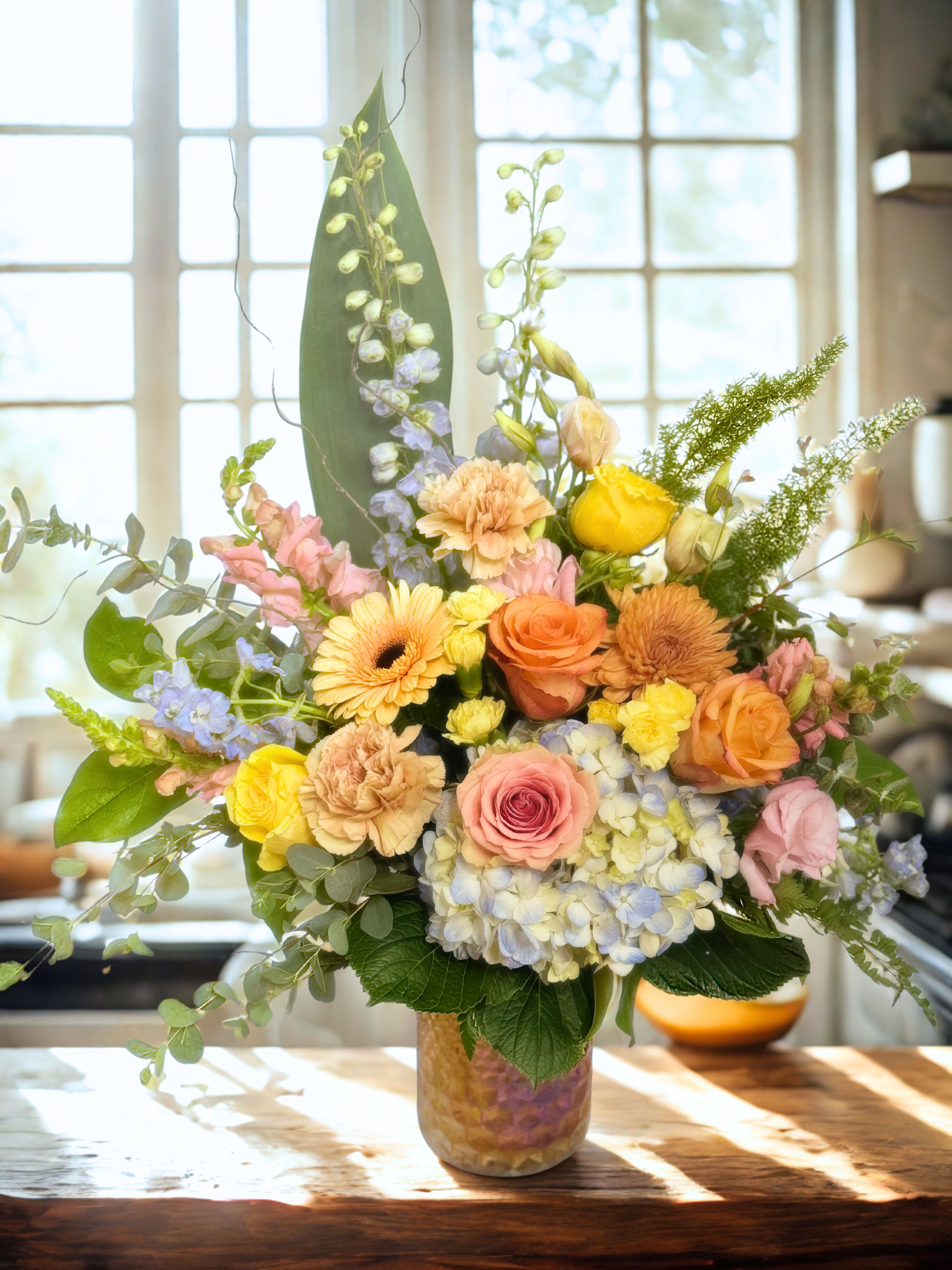 Mixed pastel flower arrangement in a glass vase