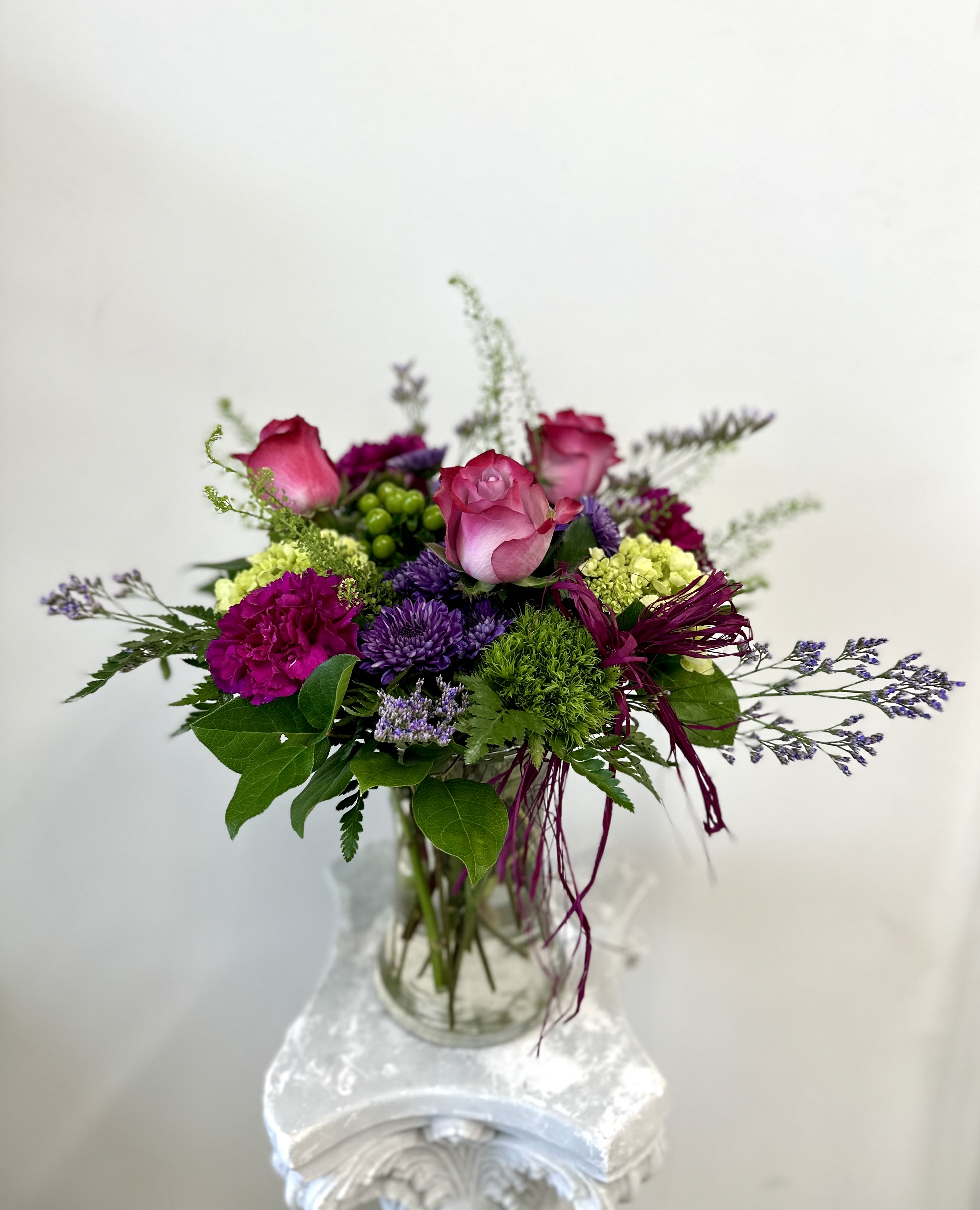 Purple Dreams by Westford Florist Art by Veny - Elevate your home decor with exquisite Purple Dreams flower arrangement by Westford Florist Art by Veny. This stunning ensemble features a captivating mix of lavender roses, purple poms, and magenta carnations that is sure to add a touch of elegance to any space. The addition of sea lavender, mini green hydrangea, and hypericum berry creates a truly mesmerizing visual appeal. Indulge in the beauty of nature with this carefully curated arrangement, perfect for adding a pop of color to your living room or workspace. Complete with magenta raffia for that extra special touch, the Purple Dreams bouquet is bound to be the centerpiece of any room. Treat yourself or surprise a loved one with this enchanting floral creation that promises to bring joy and beauty into any environment. Embrace the magic of flowers with the luxurious Purple Dreams arrangement by Westford Florist Art by Veny today.