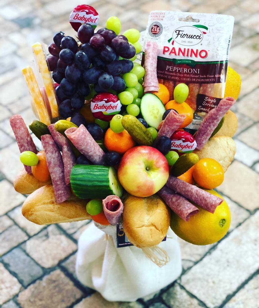 Fruit and snack bouquet with grapes, apples, cheese, salami, and bread
