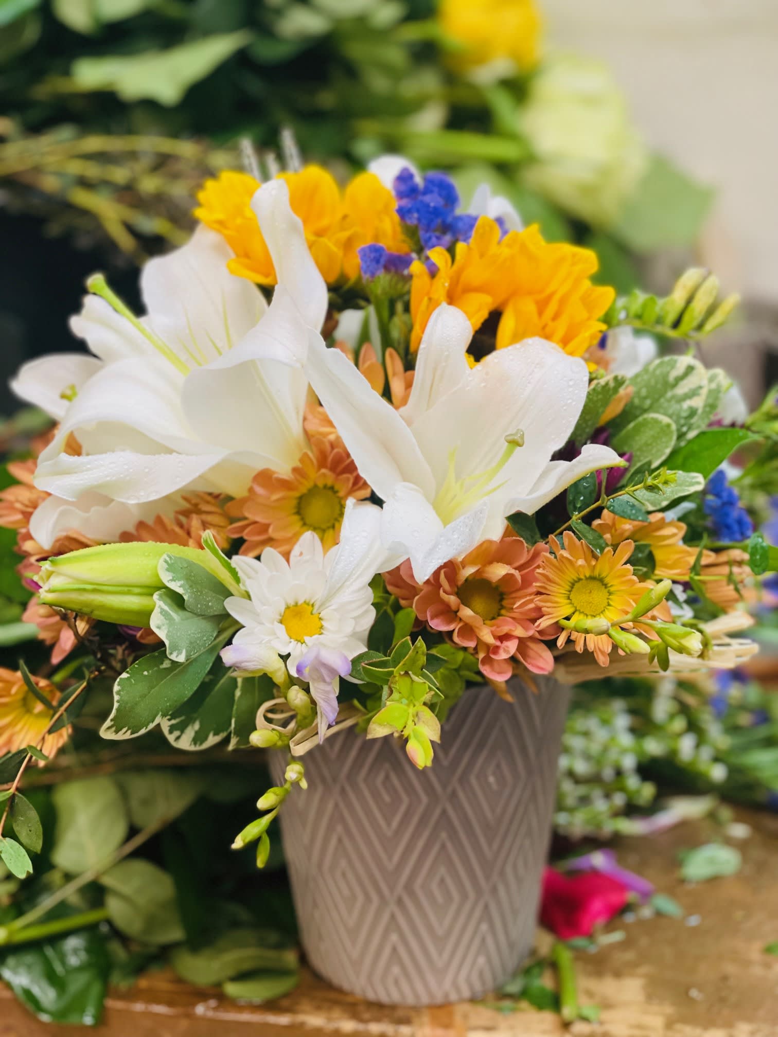 Fall is Fabulous  - Cheerful mix of daisies, lilies, sunflowers, carnations, statice in neutral white, yellow and orange tones. This design is perfect no matter the occasion or season! The container may vary depending on availability. Bouquet may be sent in a basket, a metal or a plastic container.