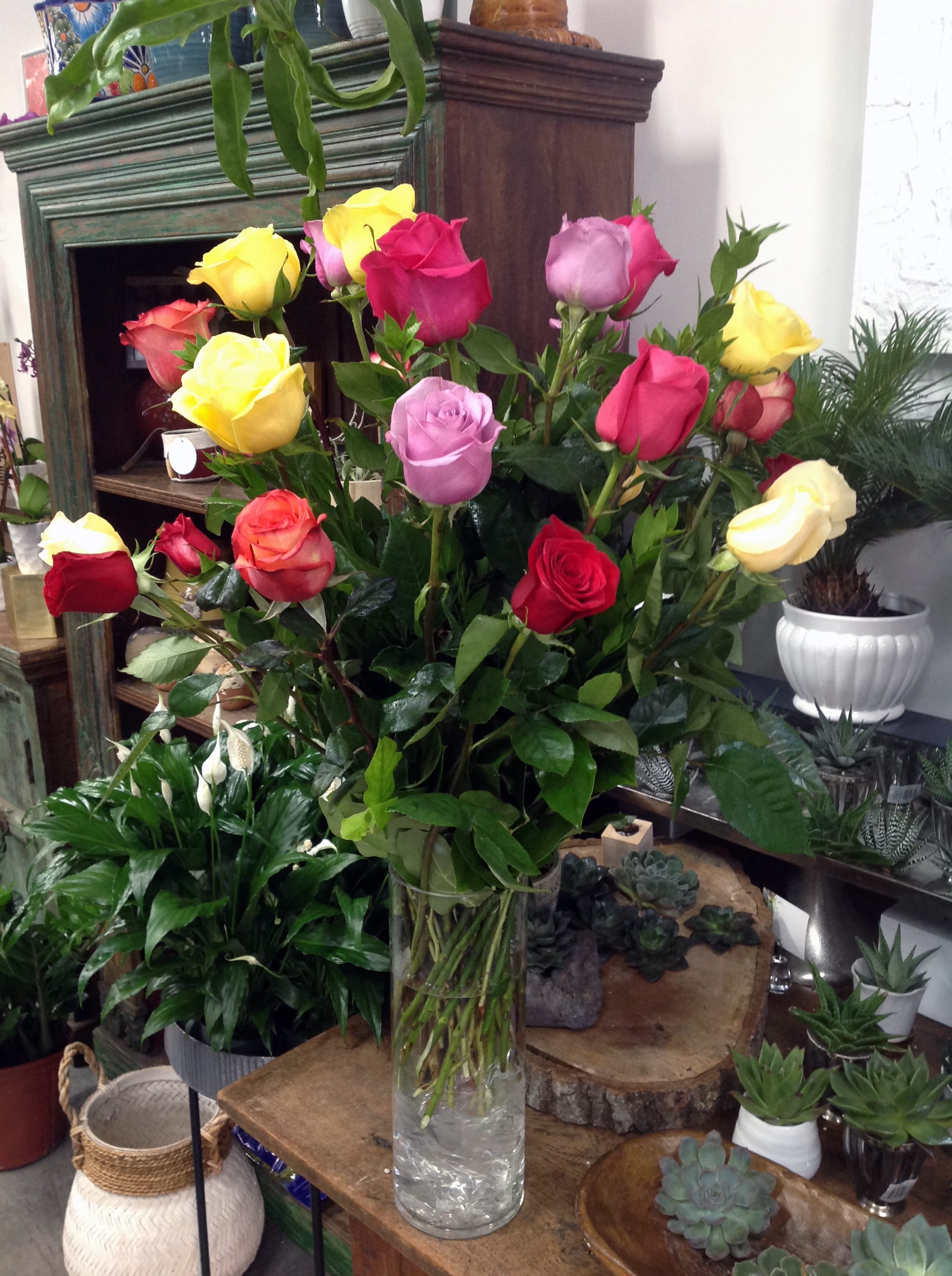 Sunrise Brooklyn - Dozen Roses - A cheerful arrangement contains one dozen long stem-colored roses in a cylinder glass vase and accentuated with greenery. Note: Valentine's Day may impact the prices and availability of this product. 