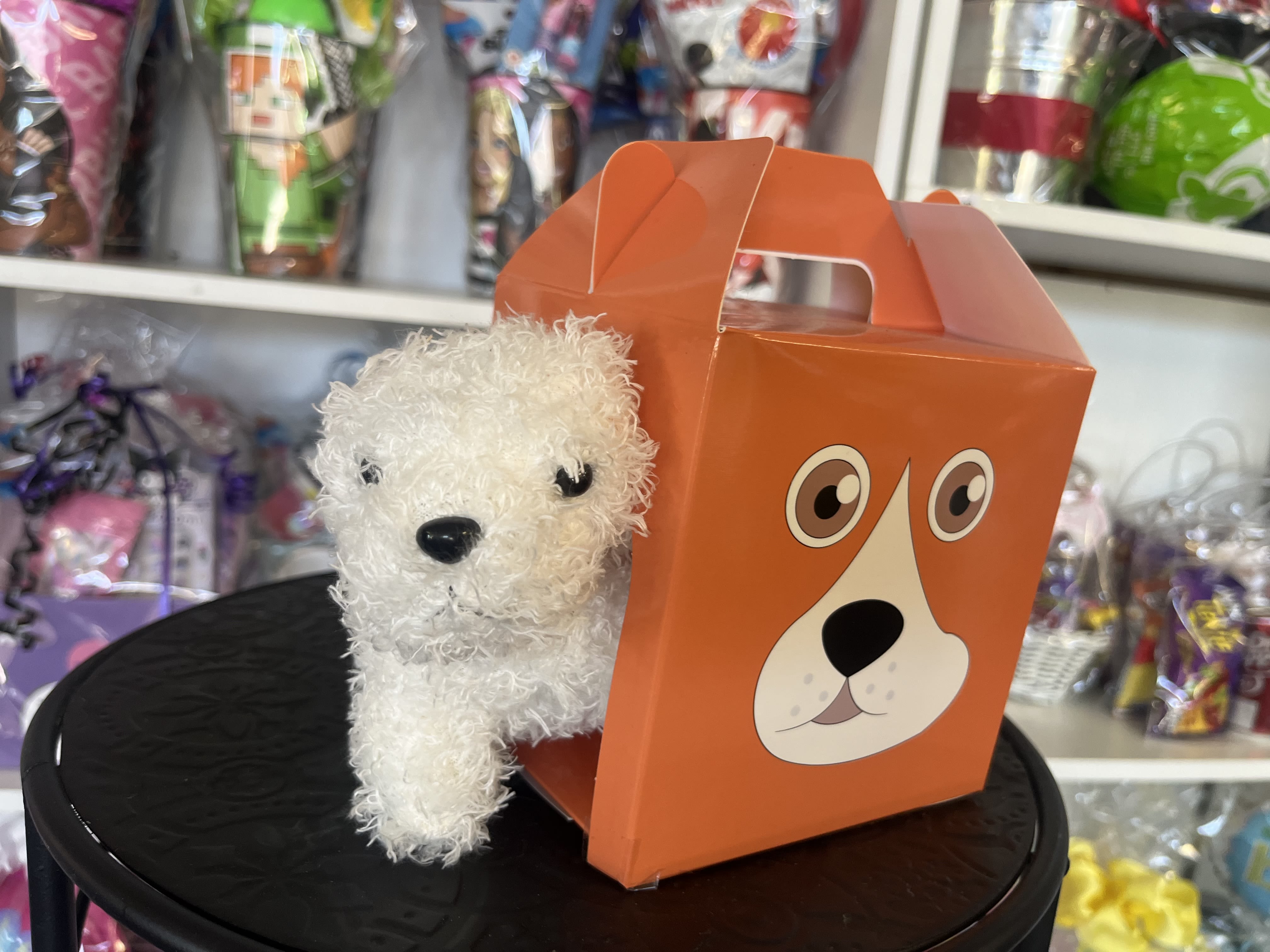 White plush dog in an orange gift box with a dog face graphic