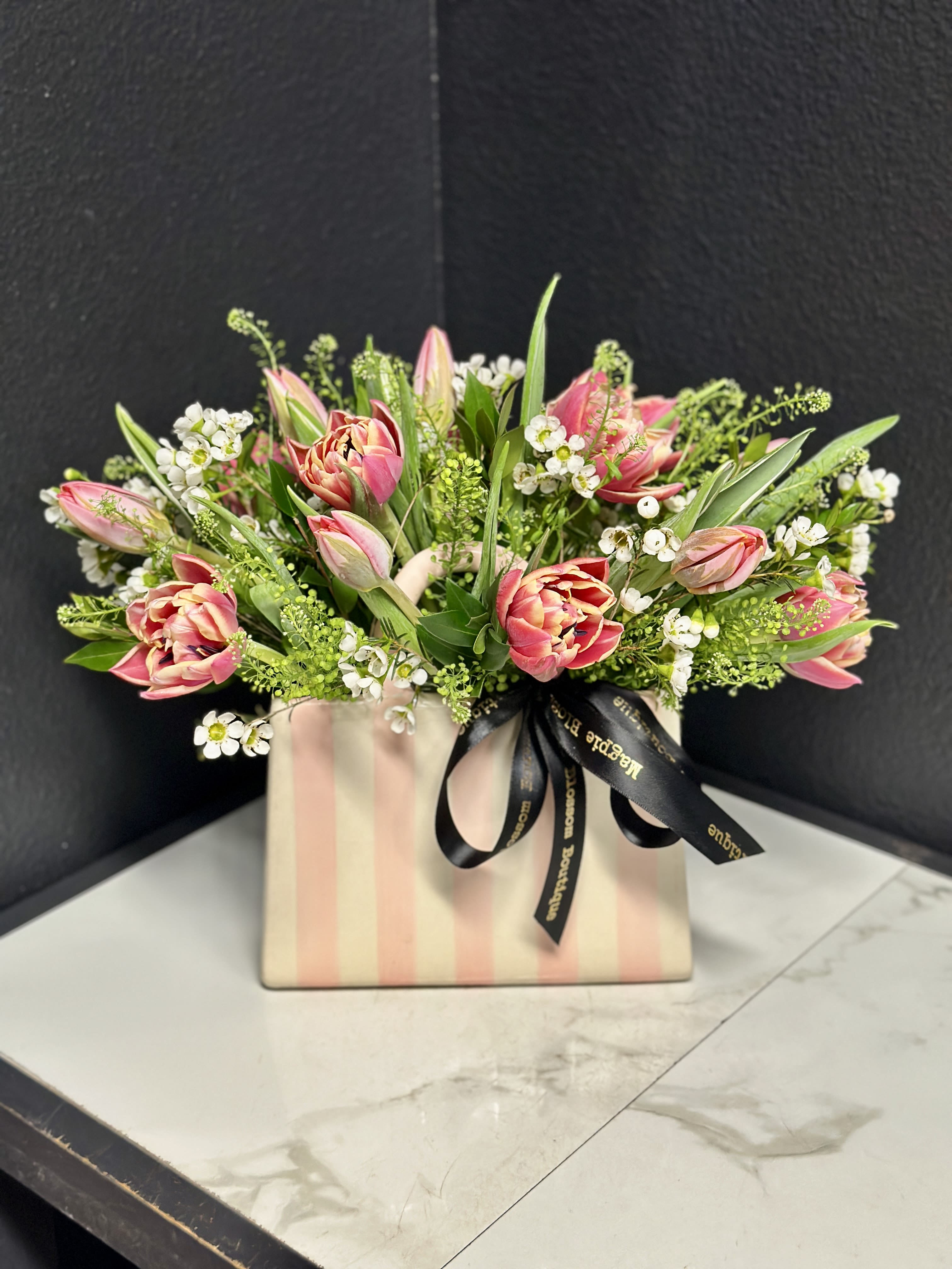 Miranda with Tulips - Perfect for Mother's Day, Birthday, or a fun just because. Our ceramic Miranda Handbag Vase features white &amp; pink vertical stripes, a glossy finish, upright handles, and is versatile for repurposing as a fun display in the home once the flowers are done.  This adorable vase is filled with Tulips and seasonal foliage and accents.  Overall design is approximately 12" H x 14" W