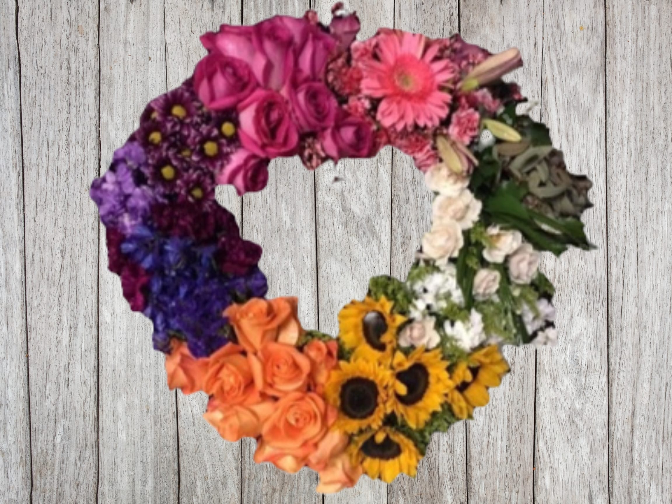Heart-shaped floral wreath with multicolored flowers on a wood background