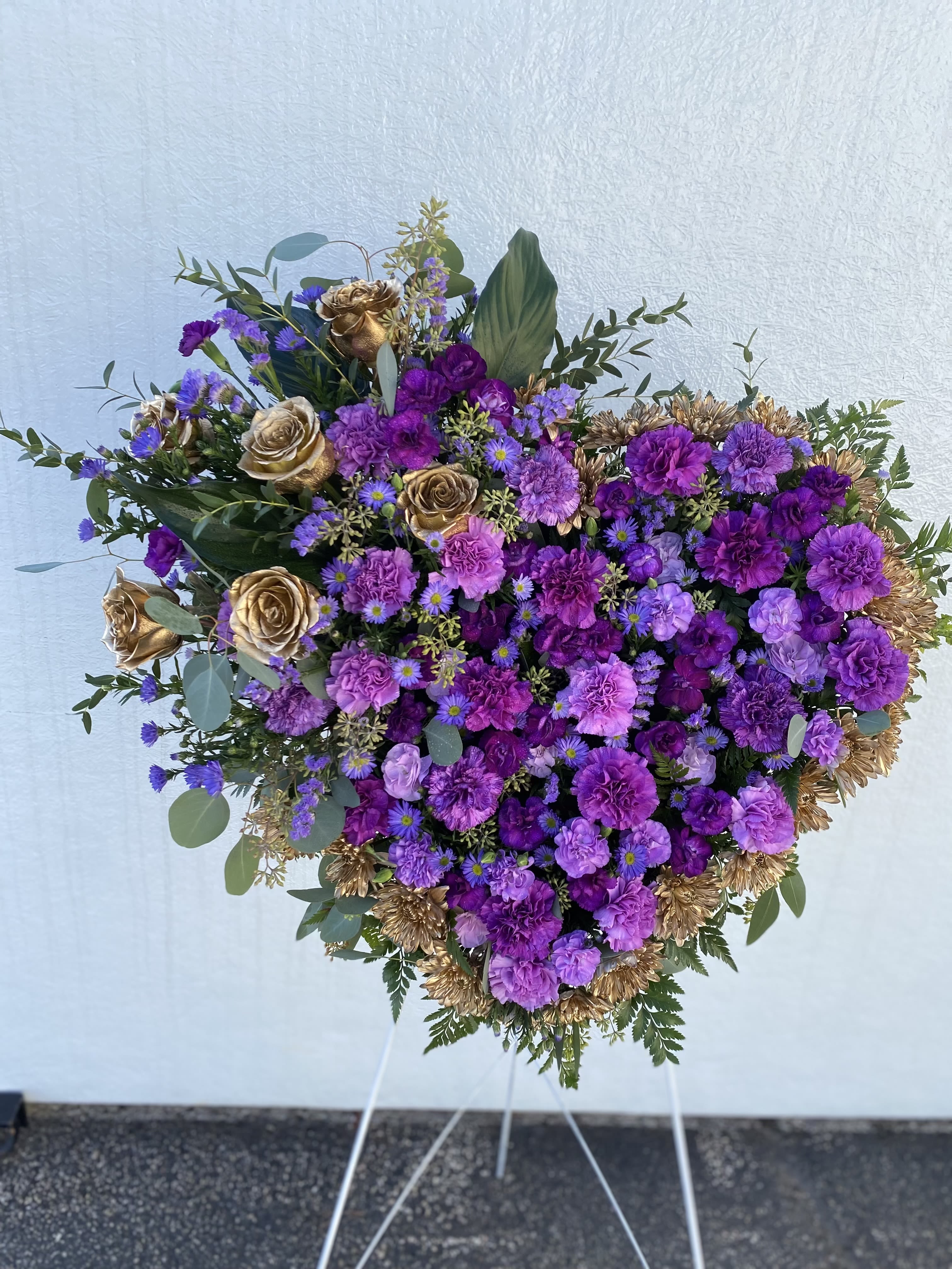 Heart-shaped purple floral spray with gold roses on a stand
